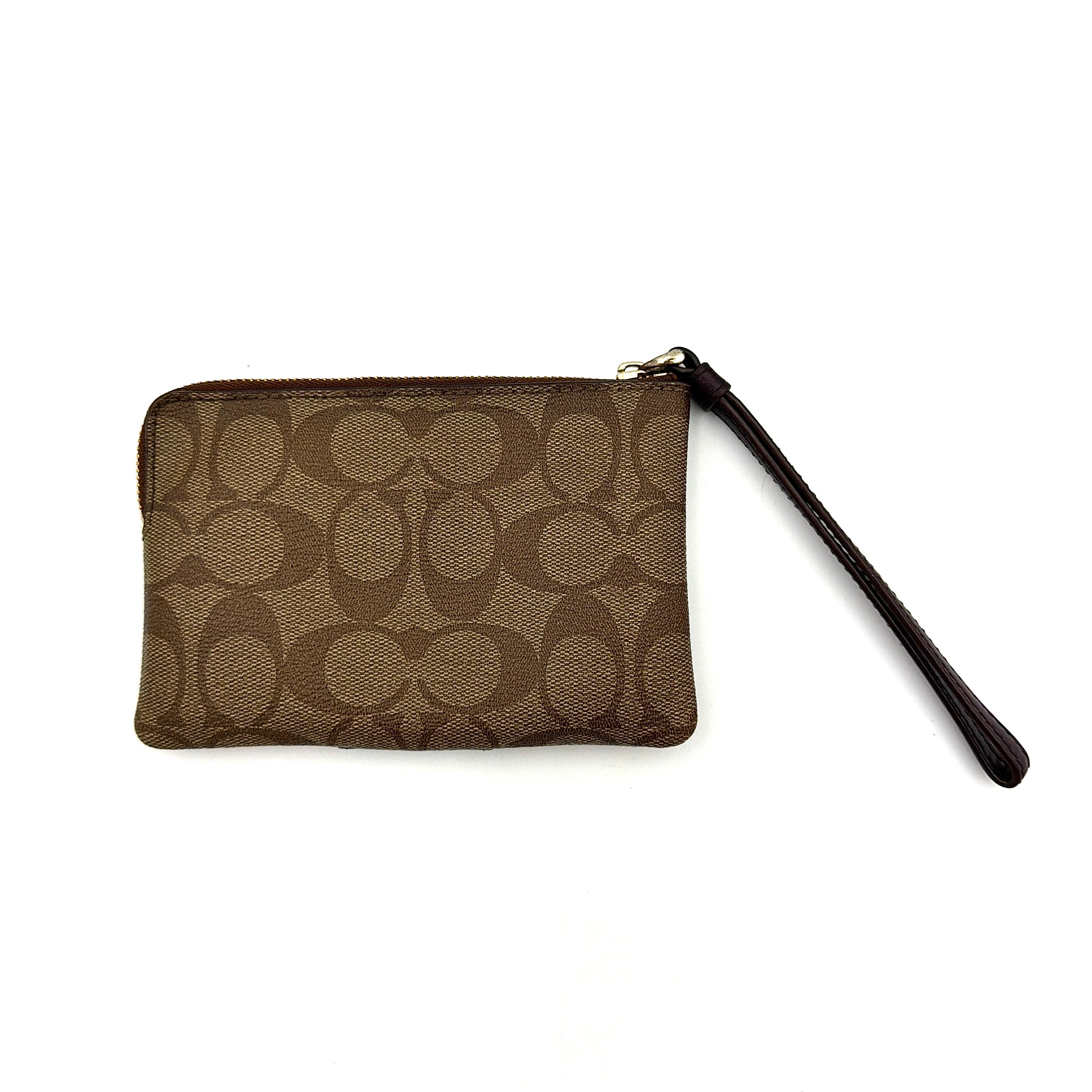 Coach Signature Stripe Corner Zip Wristlet in beige and brown canvas with a dark brown leather stripe and gold logo, shown with wristlet strap.