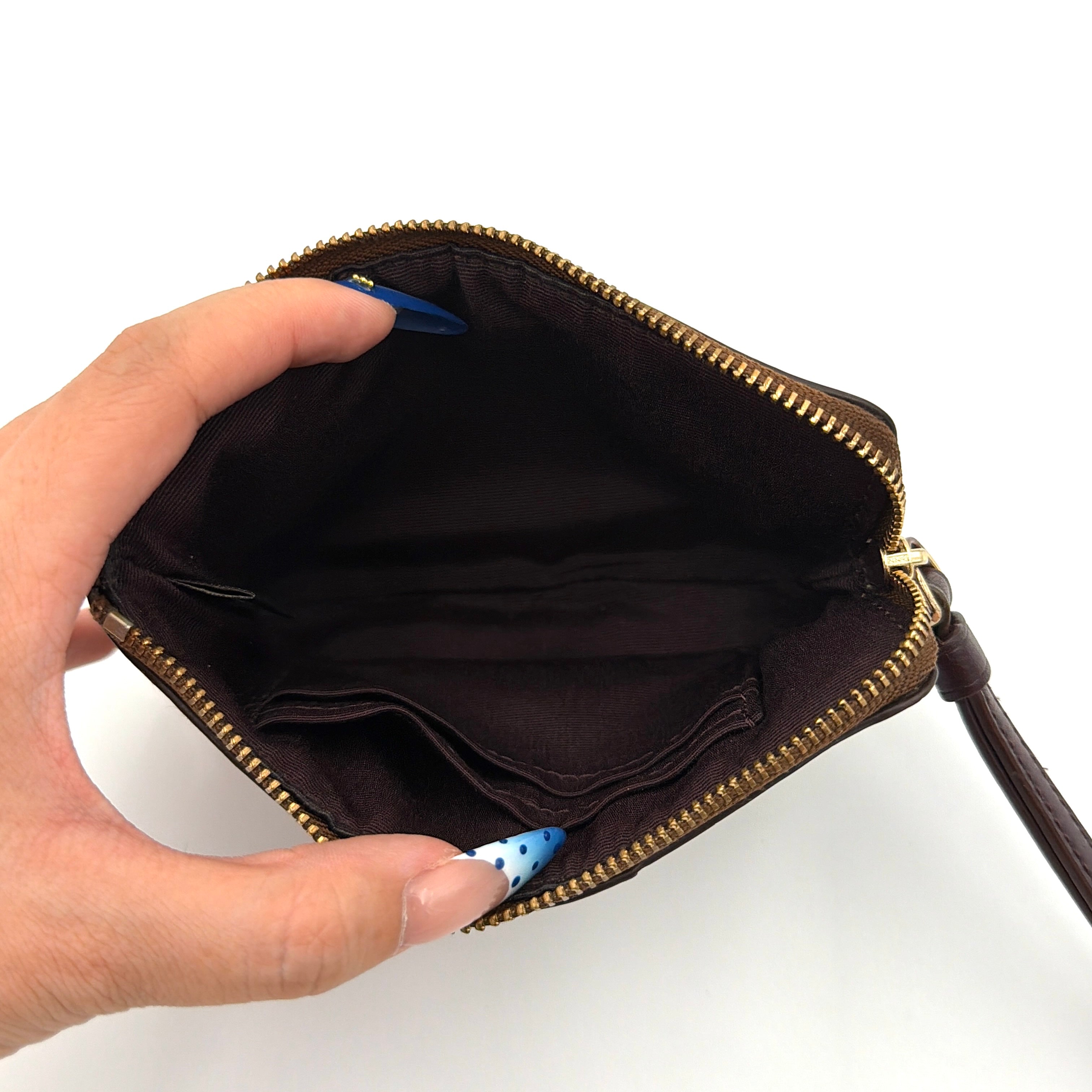 Coach Signature Stripe Corner Zip Wristlet in beige and brown canvas with a dark brown leather stripe and gold logo, shown with wristlet strap.