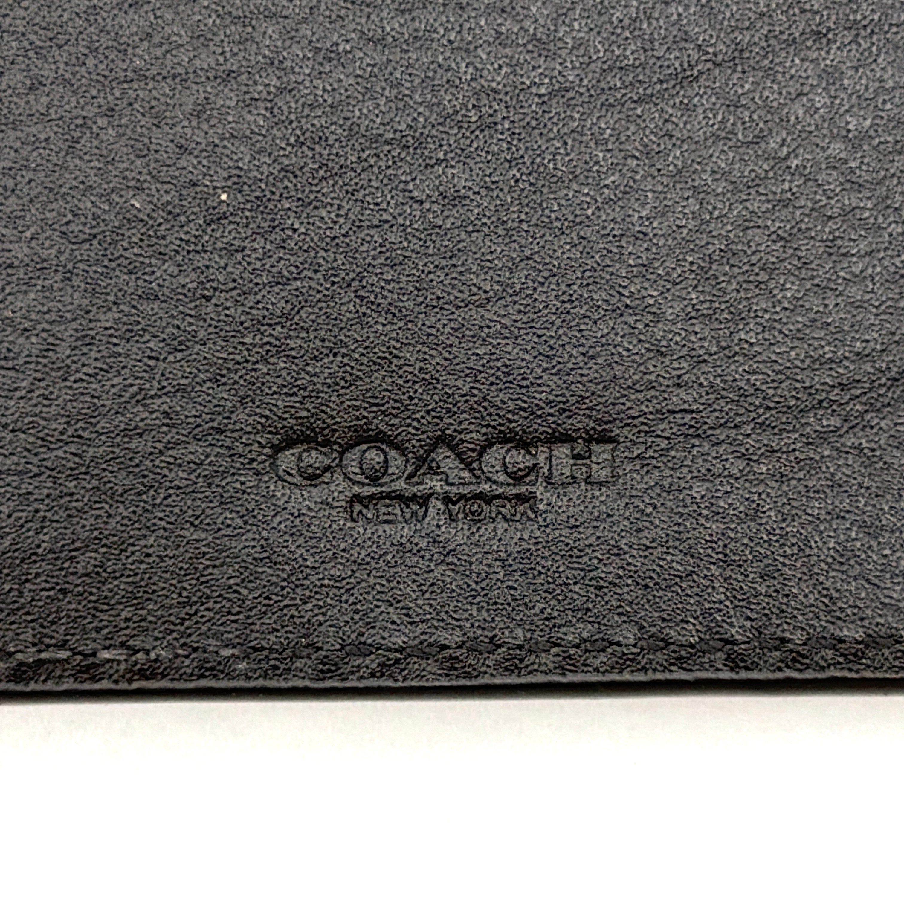 Coach Flap Long Wallet in navy blue leather with embossed logo, shown in a crisp editorial front view.