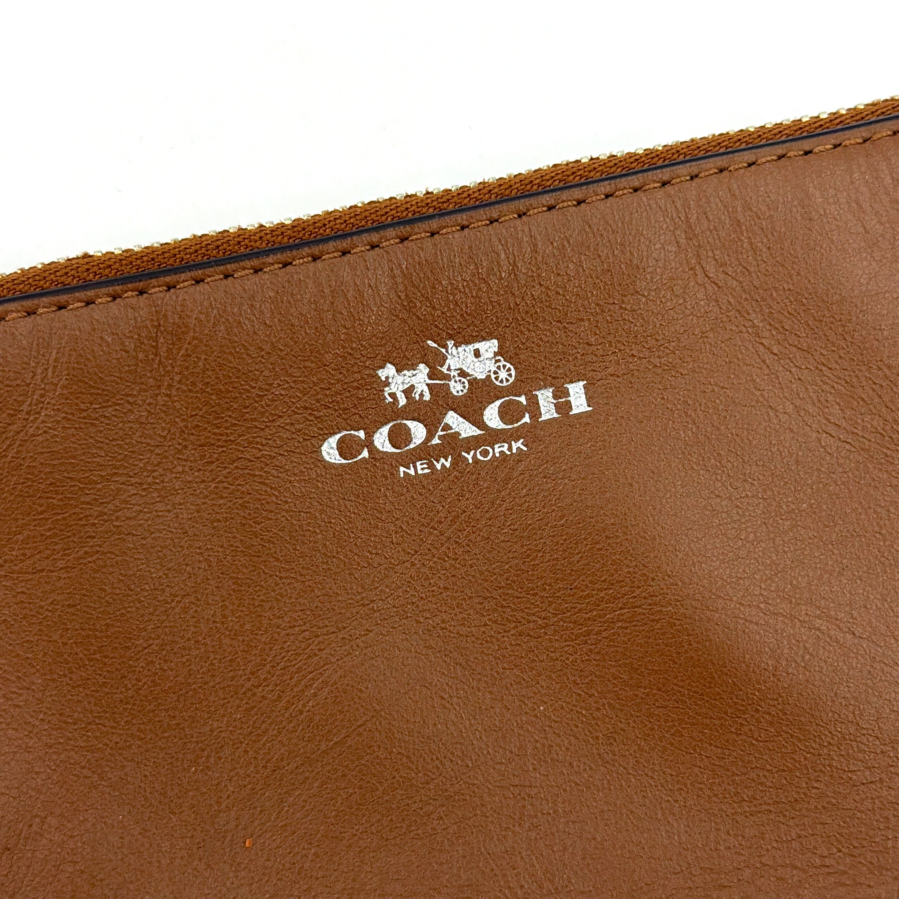 Coach Corner Zip Wristlet in smooth brown leather with silver logo and detachable wrist strap shown against a clean background.