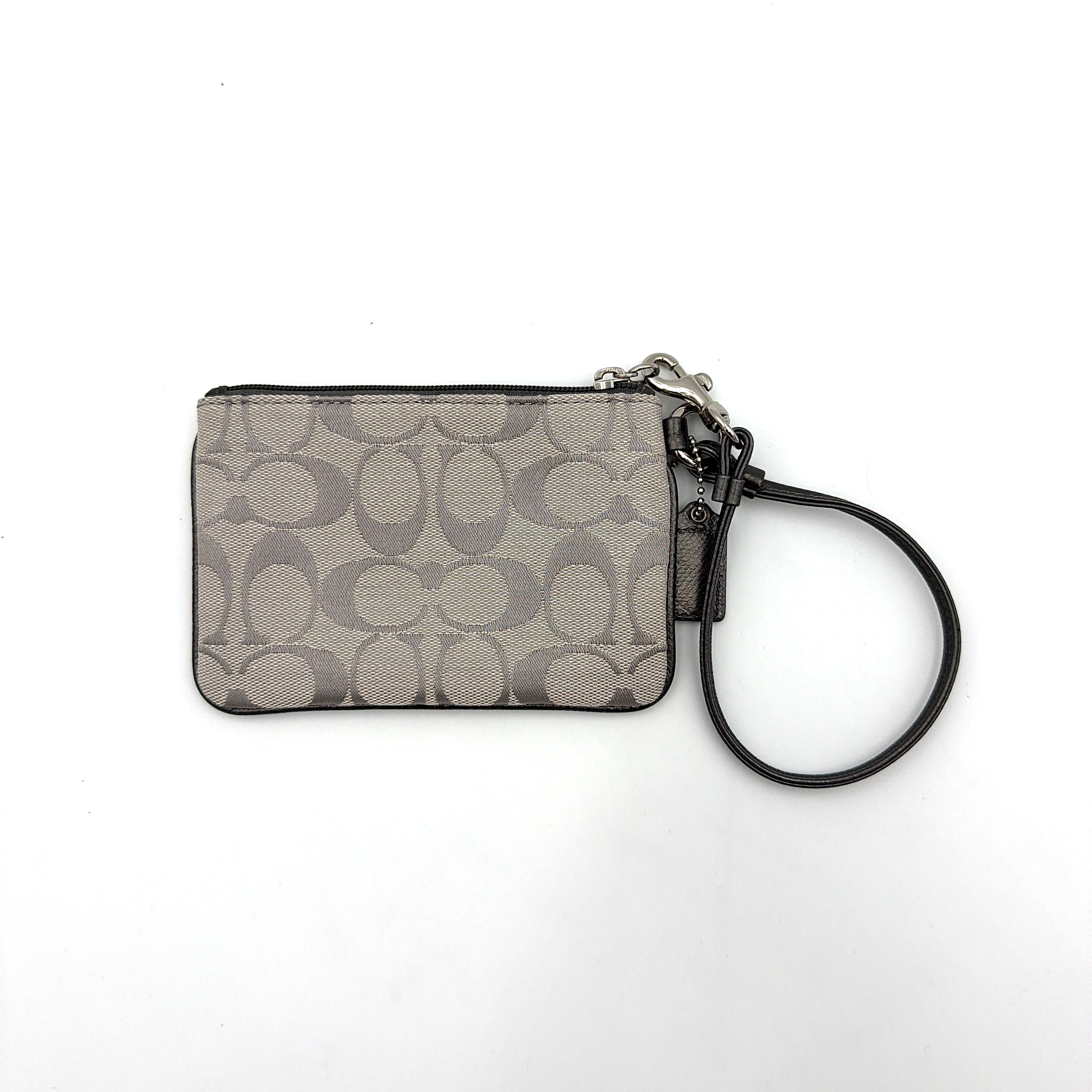 Coach Signature Canvas Corner Zip Wristlet in grey with monogram print, silver oval logo plaque, and black leather wrist strap.
