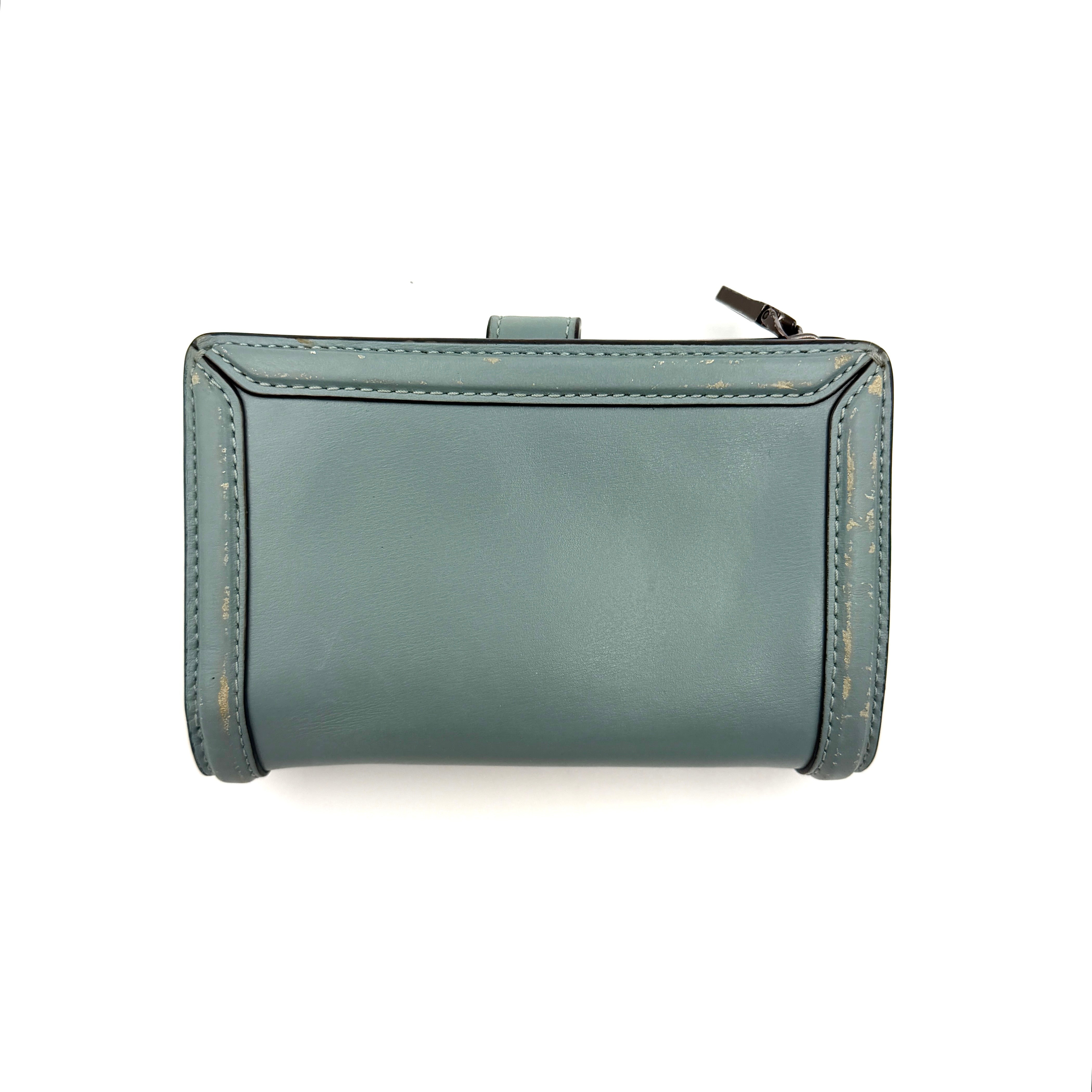 Coach Hutton Turnlock Wallet in light blue leather with signature gold turnlock clasp, showcased from the front.