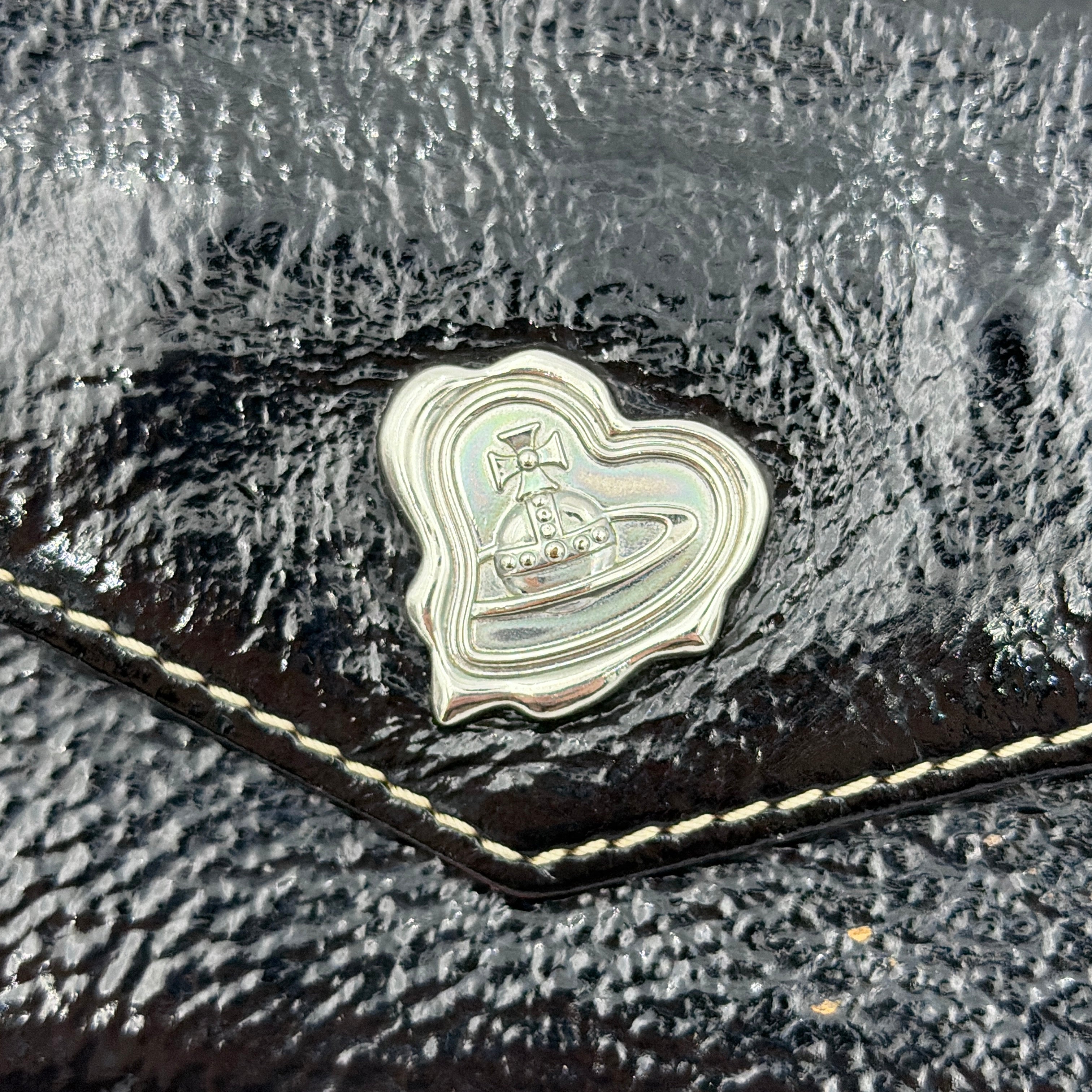 Vivienne Westwood black patent wallet featuring a silver heart orb emblem and envelope flap design.