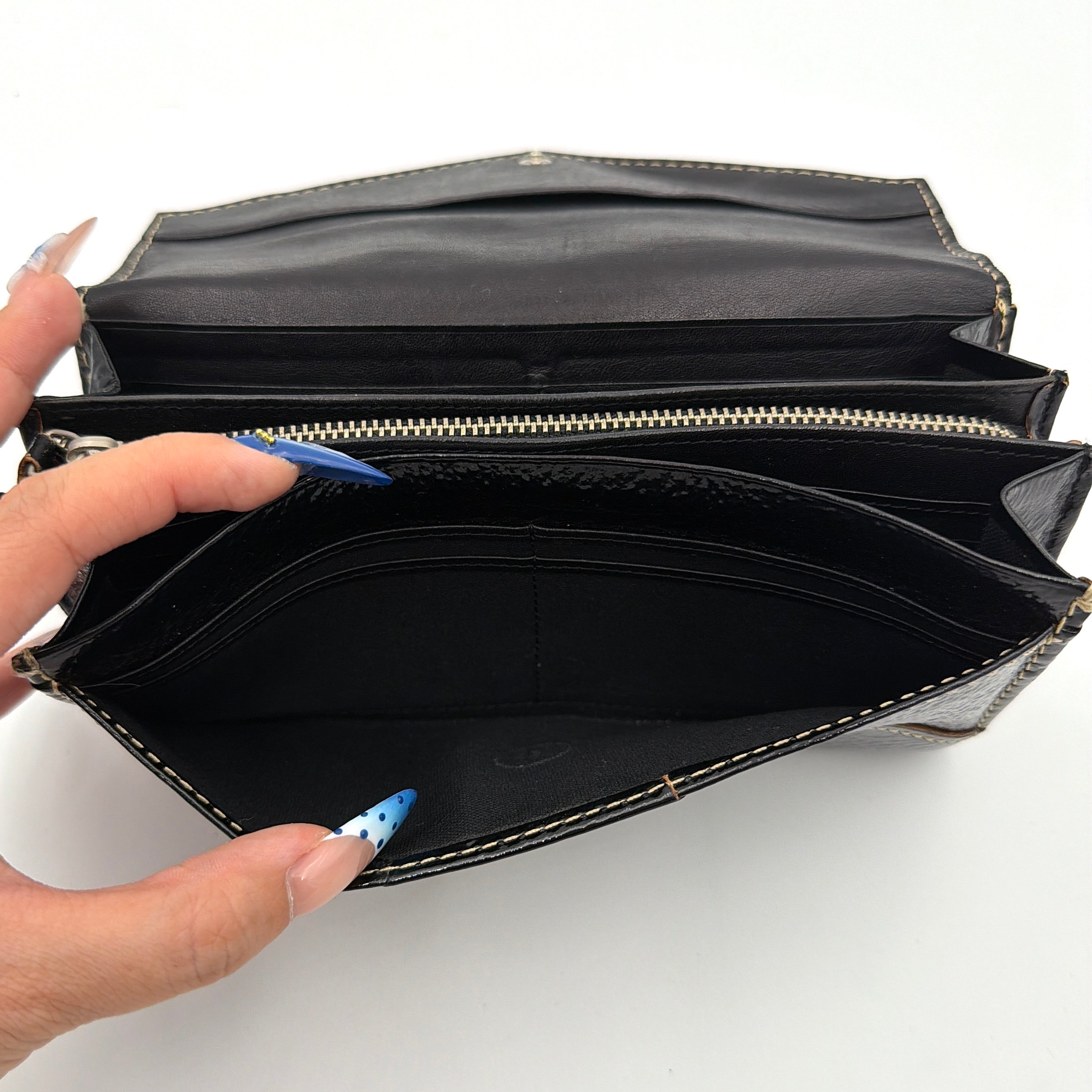 Vivienne Westwood black patent wallet featuring a silver heart orb emblem and envelope flap design.