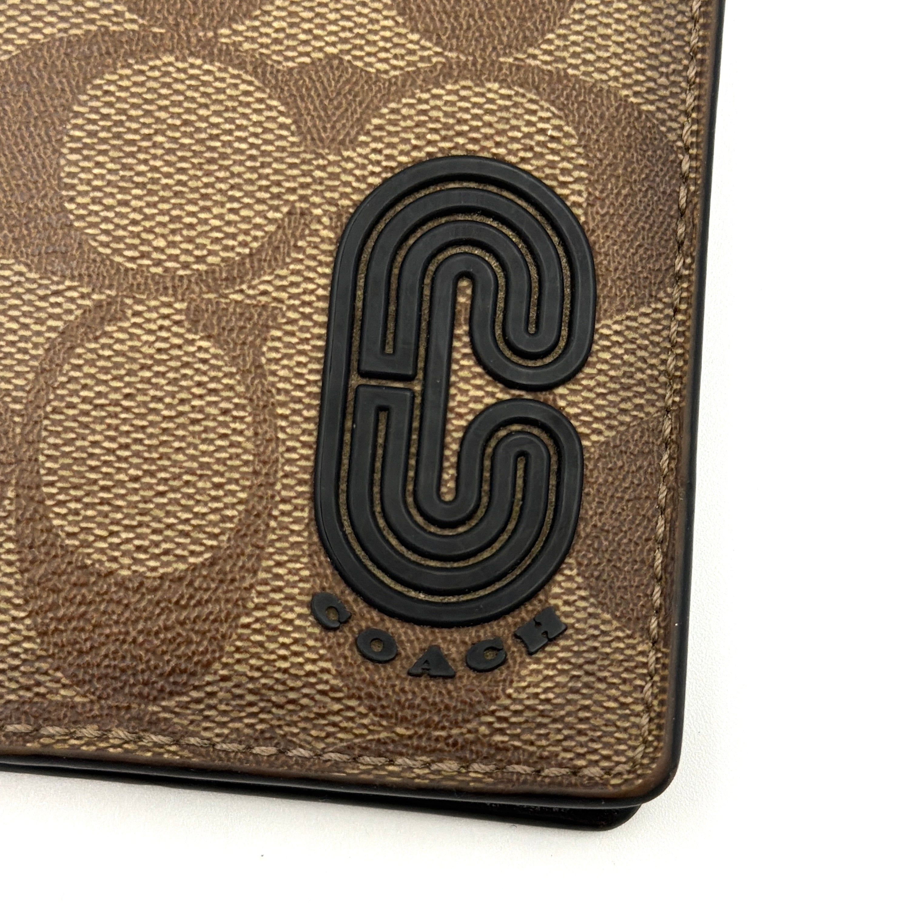 Coach Signature Canvas Patch Card Wallet in beige canvas with bold black logo patch, displayed closed against a white background.