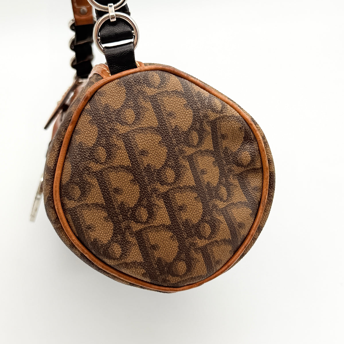 Christian Dior Romantique Heart Trotter mini barrel bag in brown canvas with black leather heart charm and chain-detailed strap.