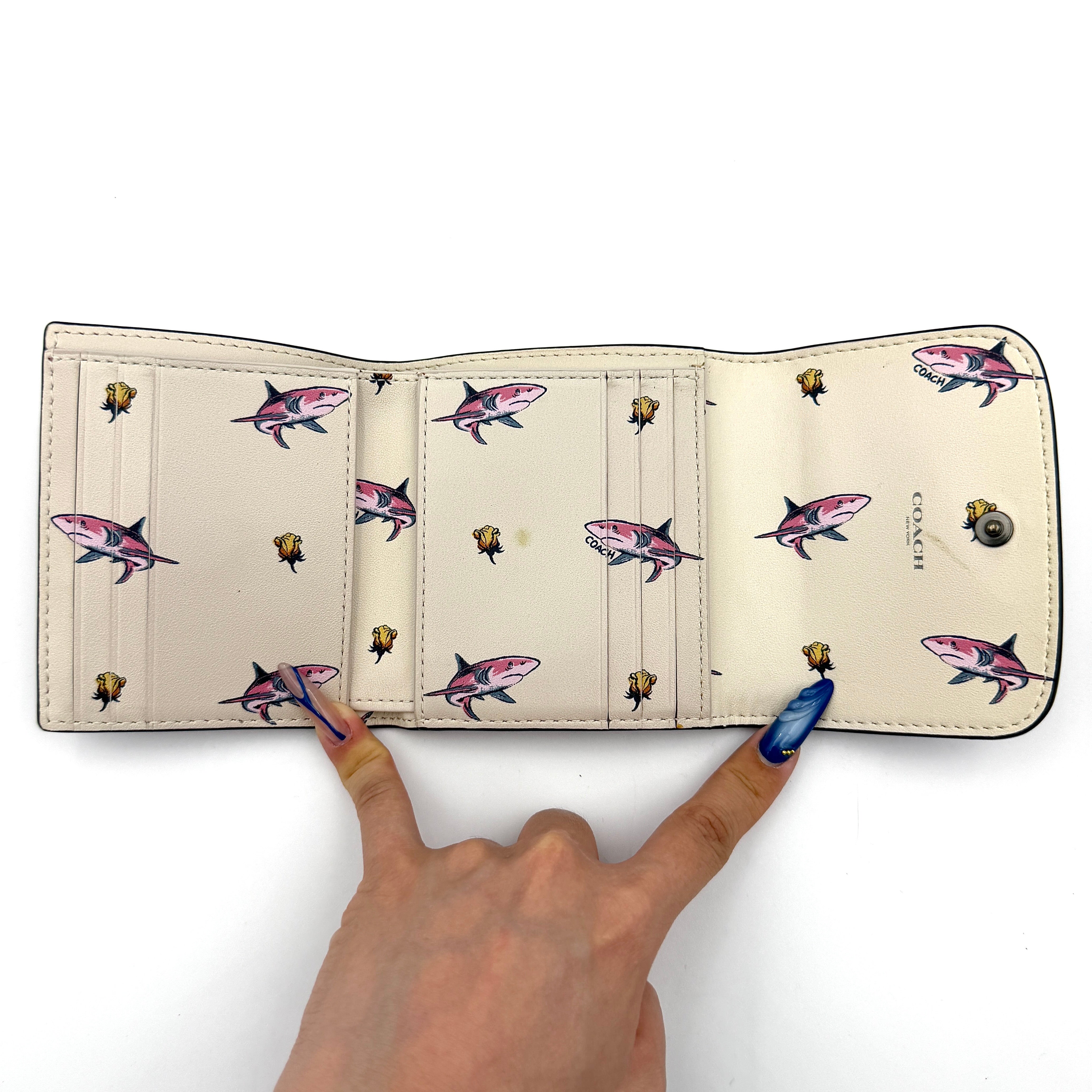 Coach small wallet in pink pebbled leather with silver logo hardware, presented closed and front-facing.