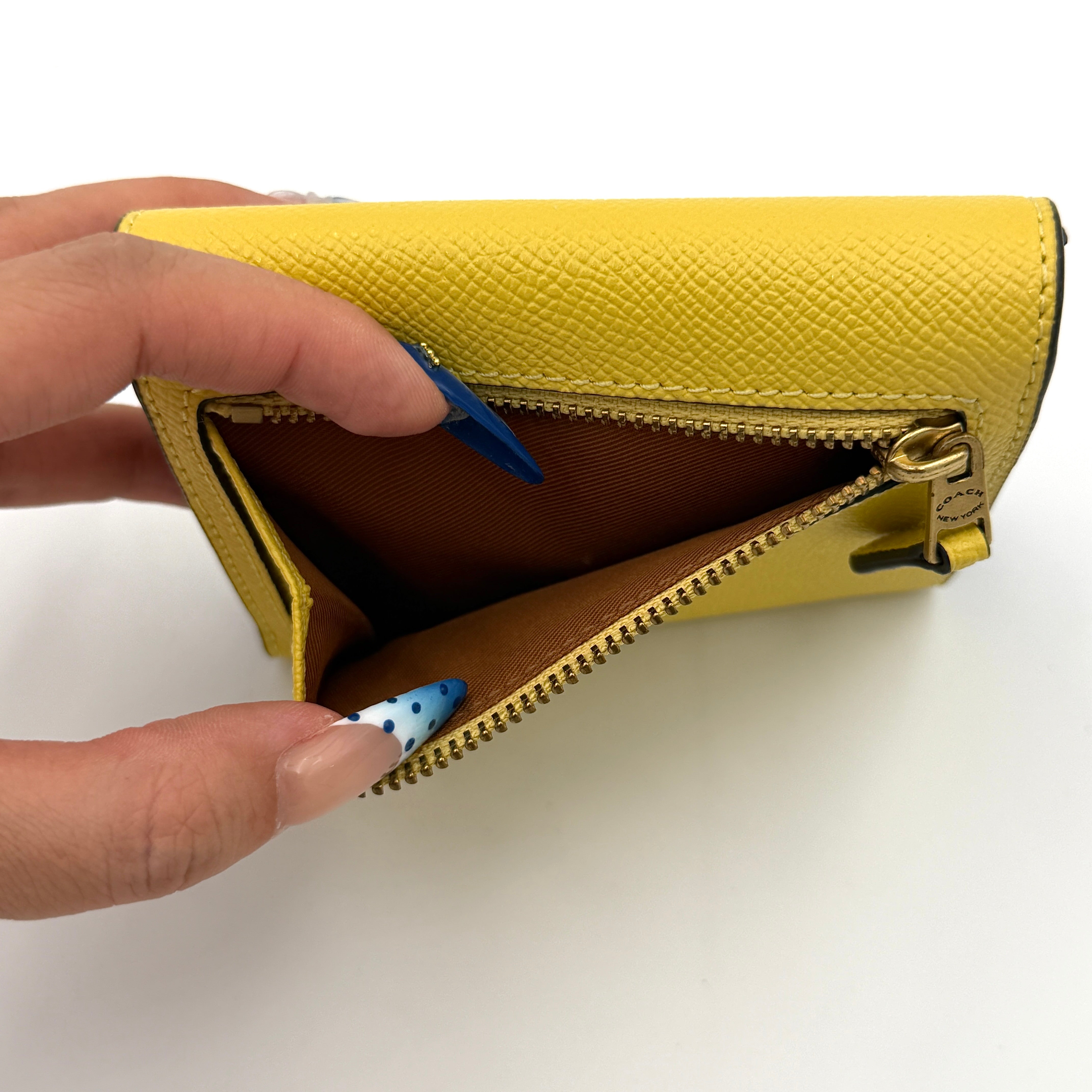 Coach Wyn Small Wallet in vibrant yellow leather with gold-tone 'C' detail on the envelope flap.