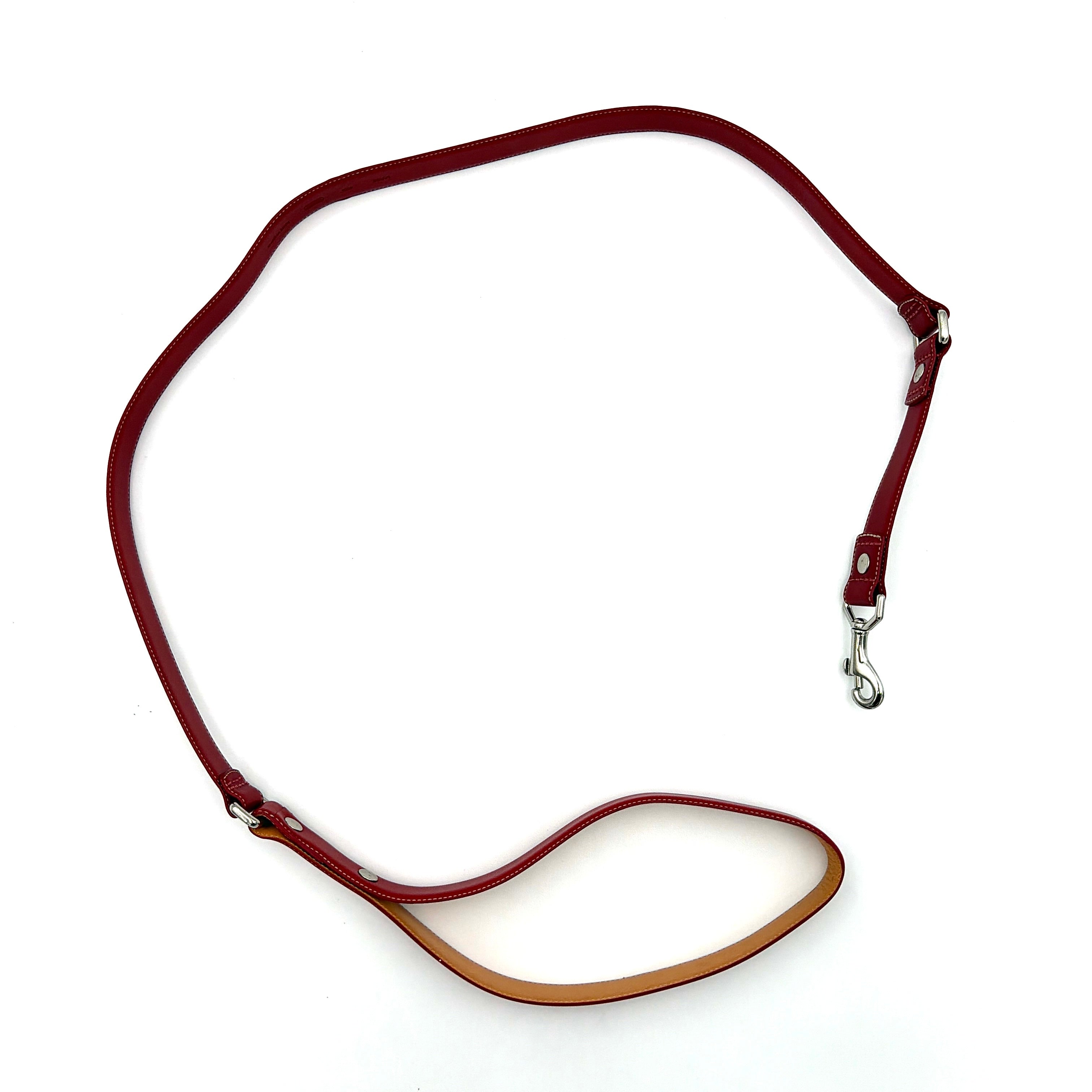 Coach leather pet leash in rich red with silvertone hardware and white contrast stitching, elegantly coiled to showcase its supple construction.