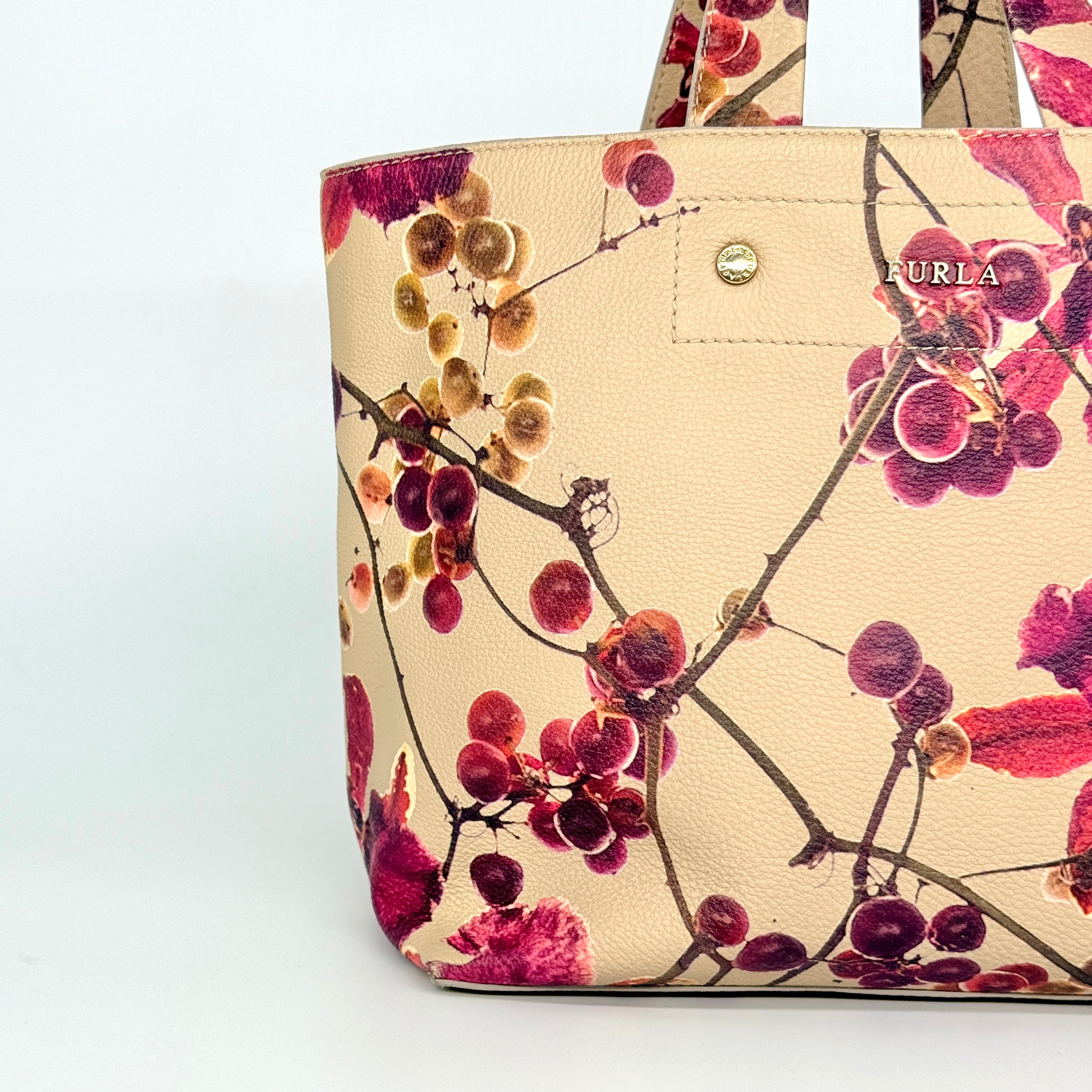 Furla beige leather tote bag adorned with a bold magenta and plum floral print, featuring structured short handles.