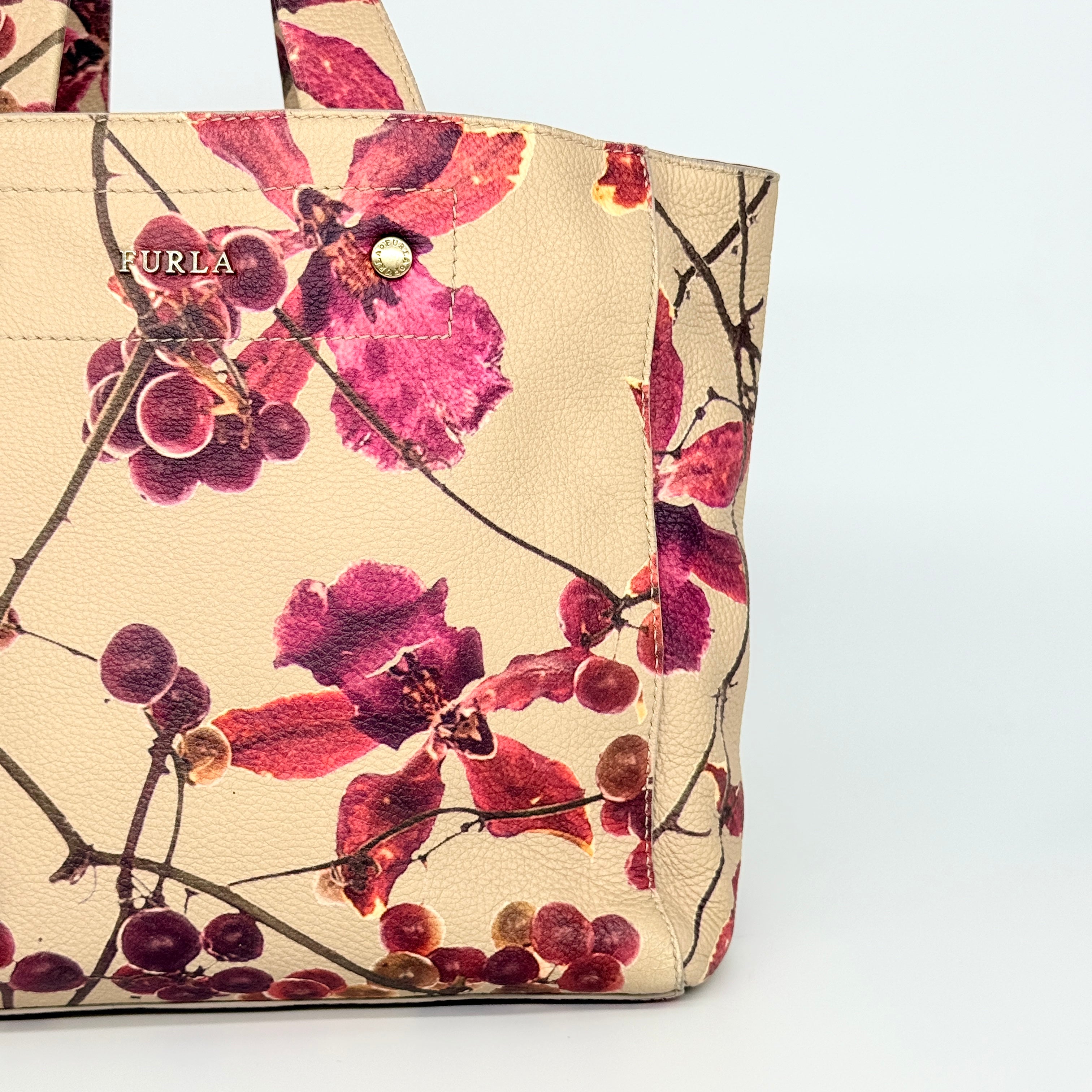 Furla beige leather tote bag adorned with a bold magenta and plum floral print, featuring structured short handles.