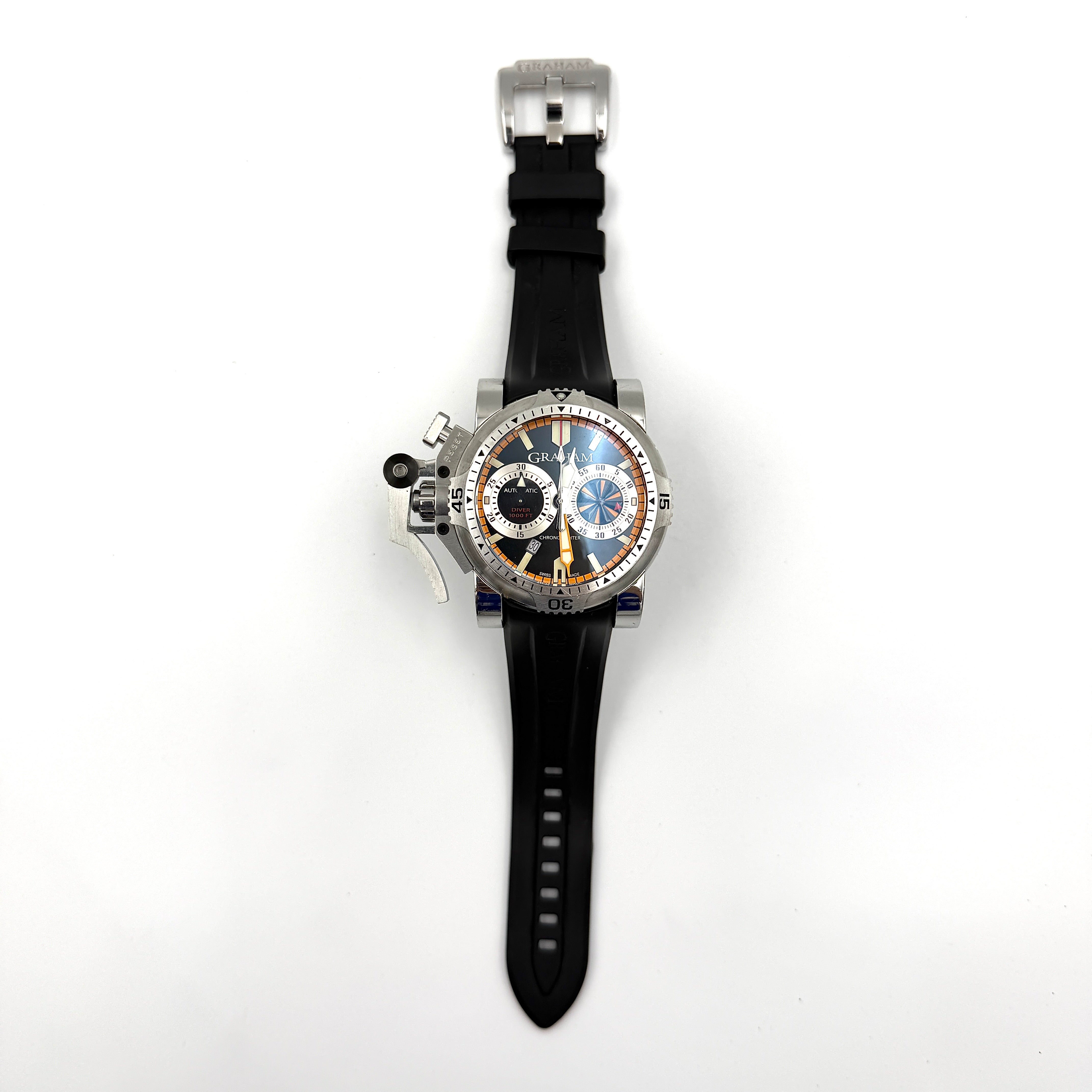 The Graham Chronofighter Oversize Diver 2OVES.B15A watch displayed in its signature round Graham London presentation case, showcasing its bold black dial, prominent chronograph trigger, and black rubber strap.