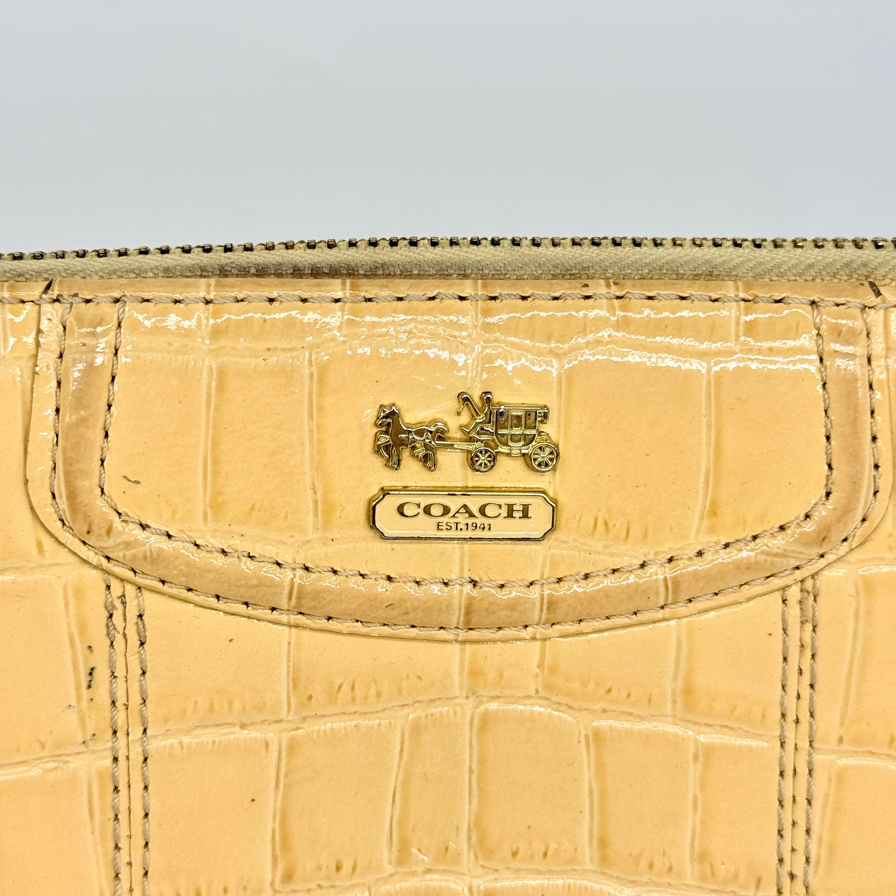 Coach beige croc-embossed zip around wallet with gold hardware and a sleek, structured silhouette.