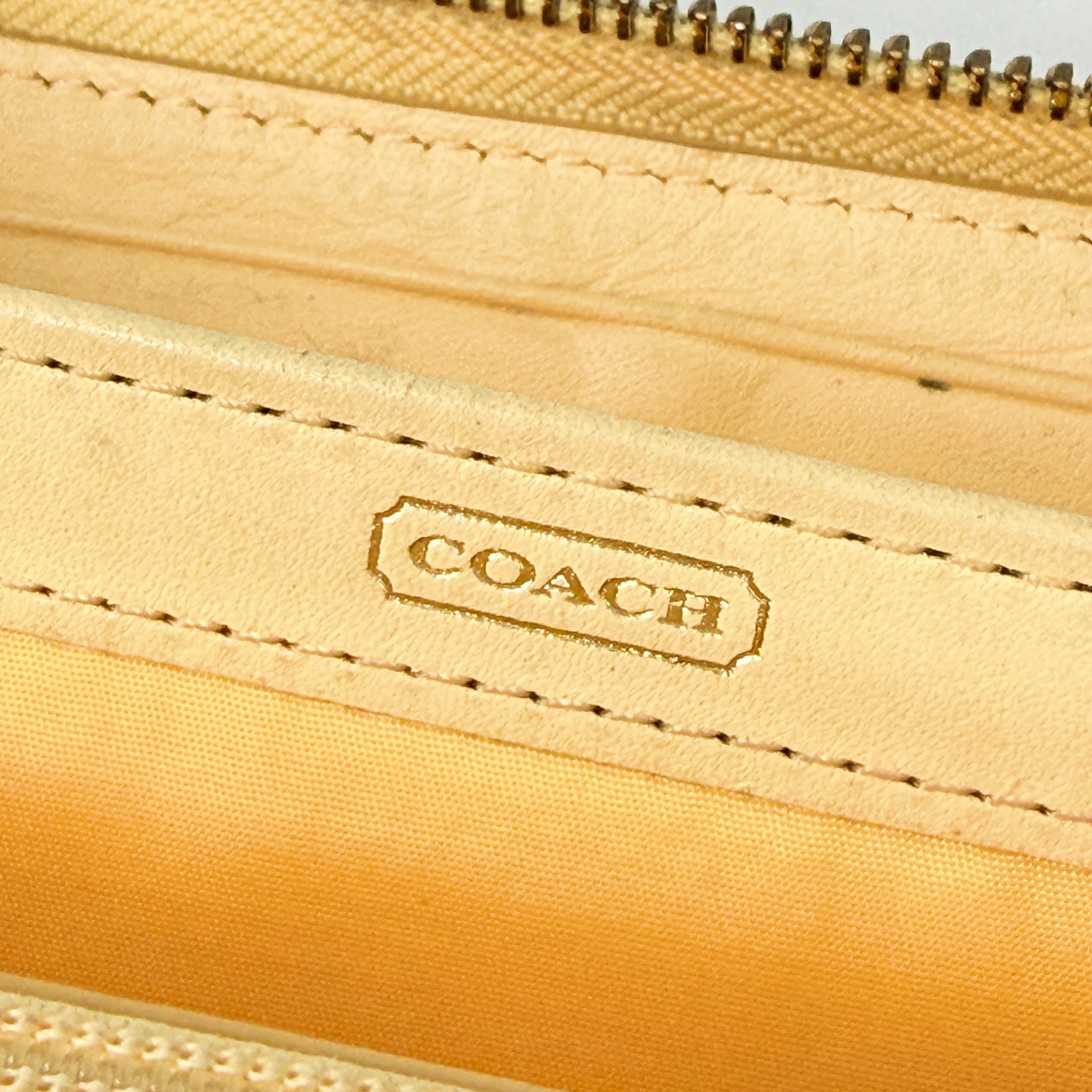 Coach beige croc-embossed zip around wallet with gold hardware and a sleek, structured silhouette.