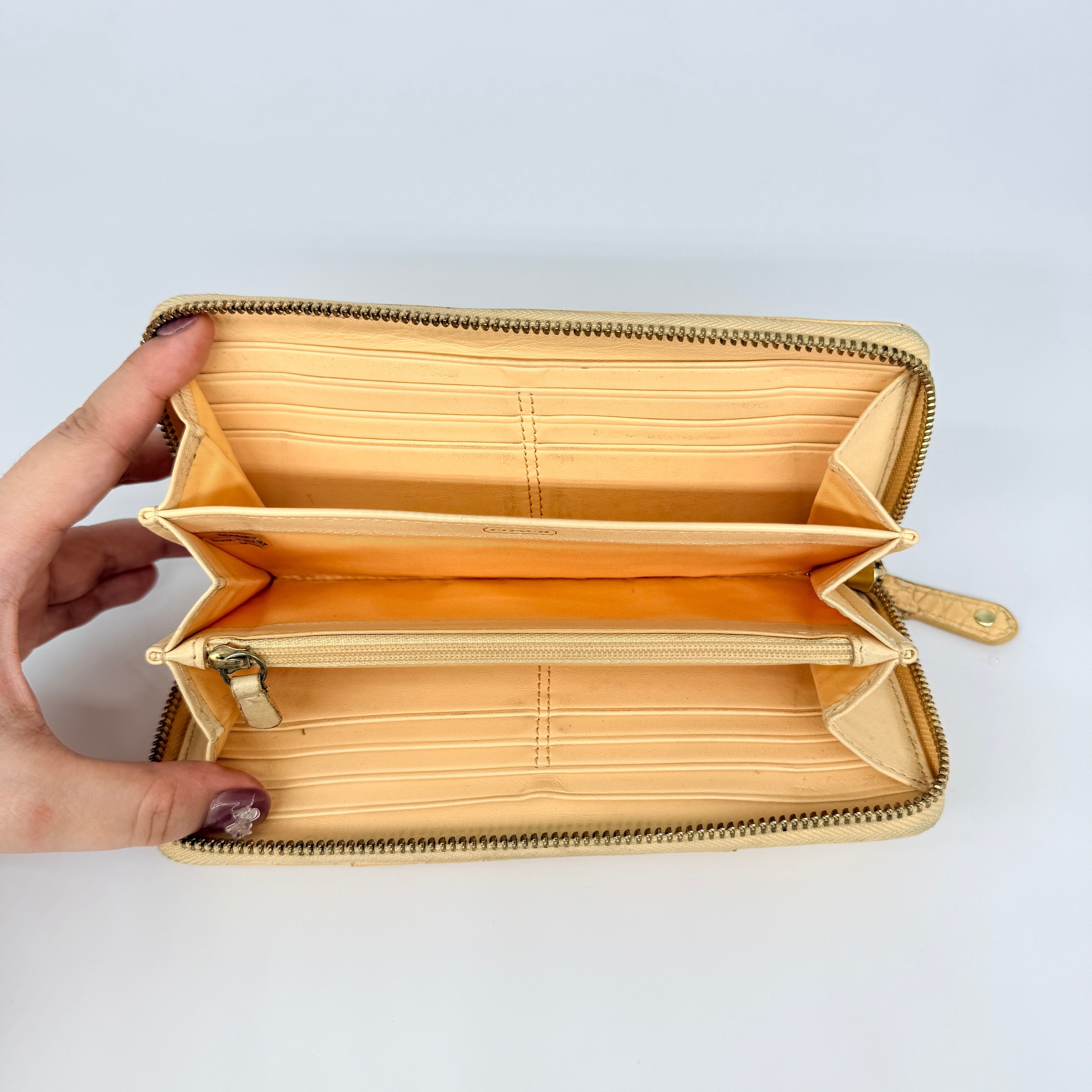 Coach beige croc-embossed zip around wallet with gold hardware and a sleek, structured silhouette.
