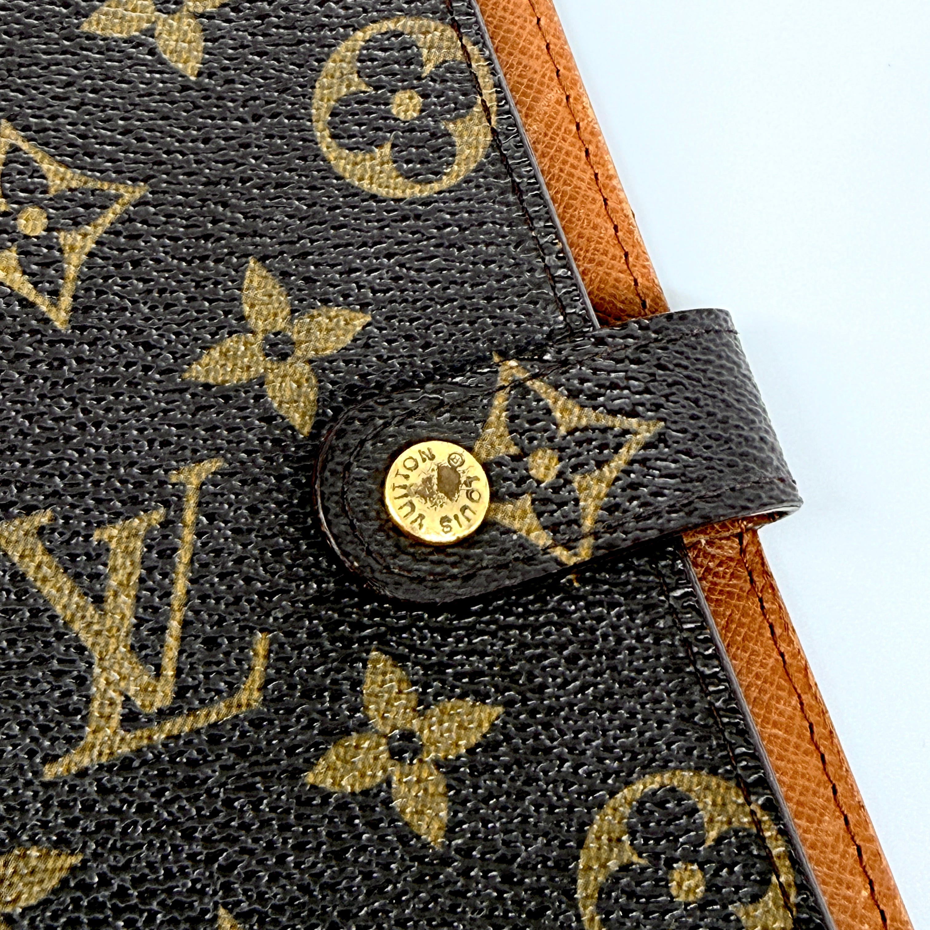 Louis Vuitton Monogram Agenda Cover in brown canvas with gold snap closure, displayed against a white background.