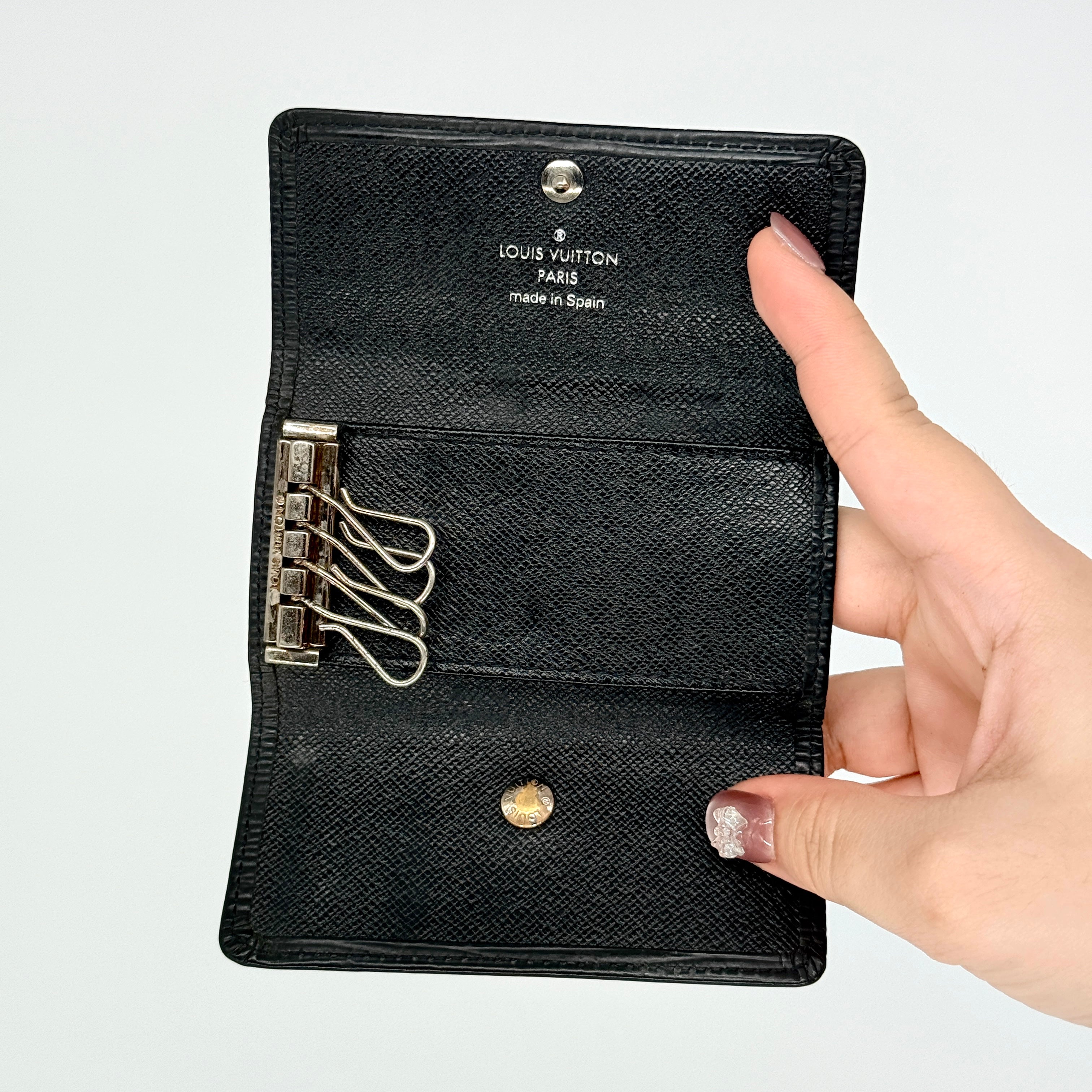 Louis Vuitton Epi Leather key case in black with silver-tone key hooks and snap closure, photographed against a clean white background.