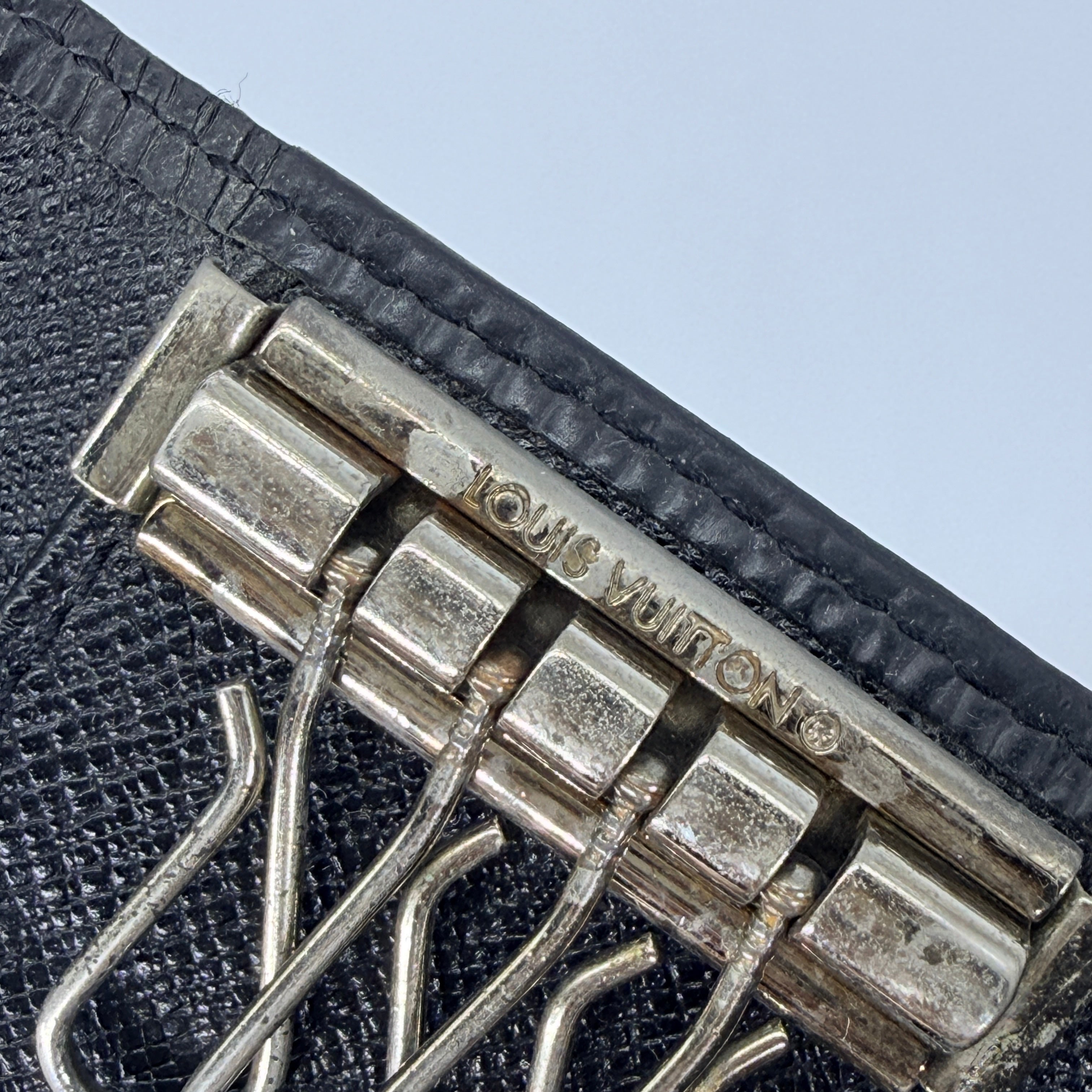 Louis Vuitton Epi Leather key case in black with silver-tone key hooks and snap closure, photographed against a clean white background.