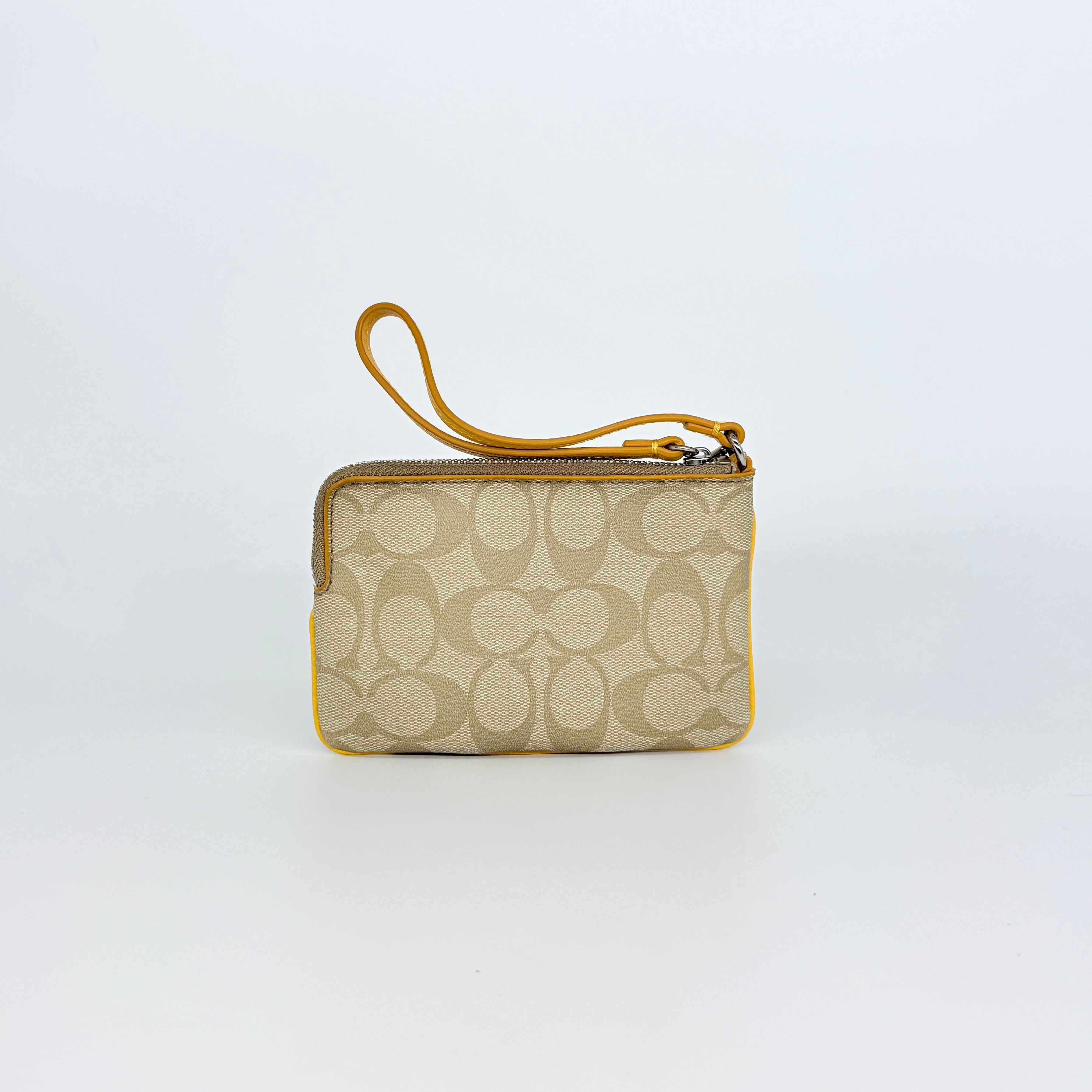 Coach Signature Stripe Corner Zip Wristlet in beige canvas with bold yellow leather stripe, silver hardware, and wrist strap displayed on a white background.