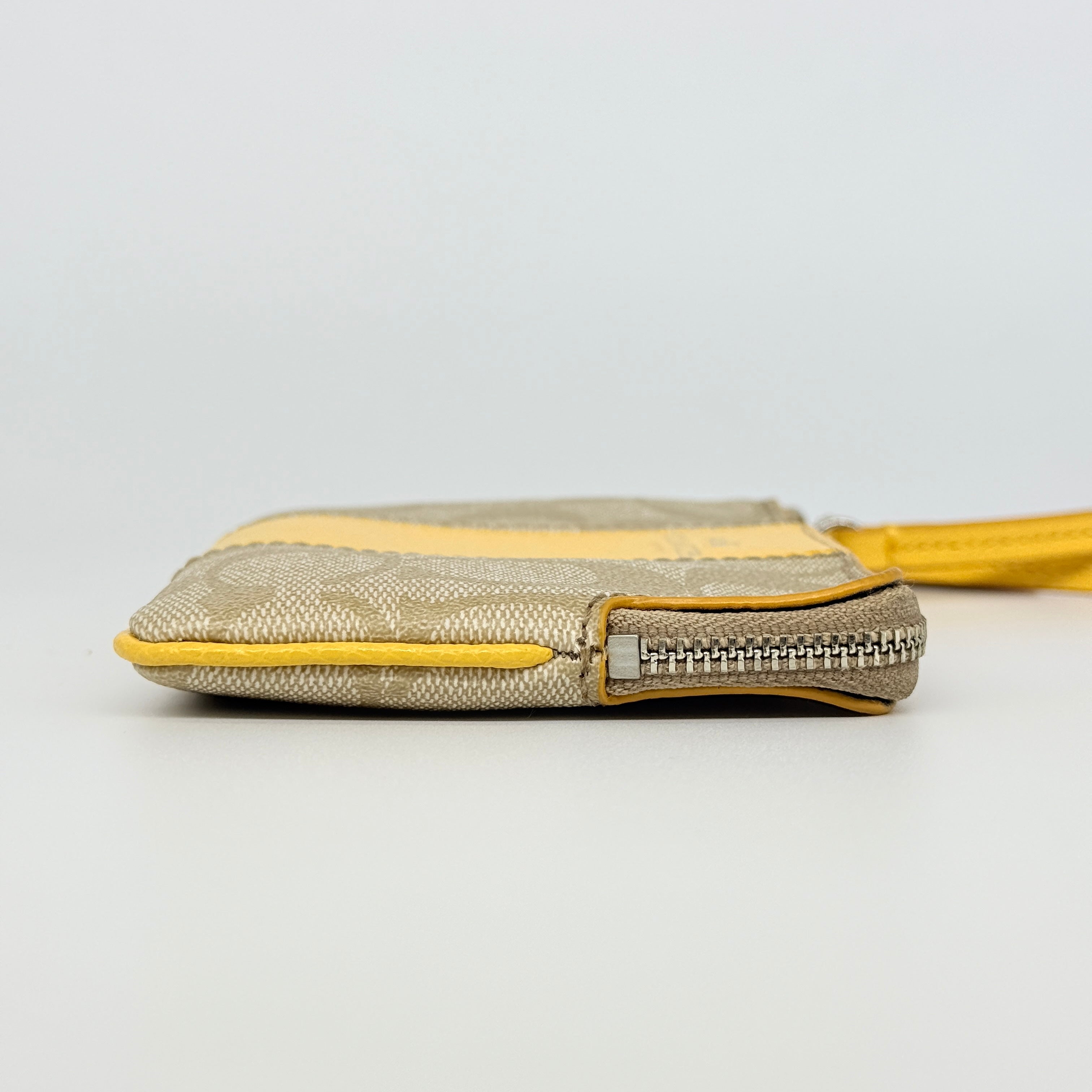 Coach Signature Stripe Corner Zip Wristlet in beige canvas with bold yellow leather stripe, silver hardware, and wrist strap displayed on a white background.