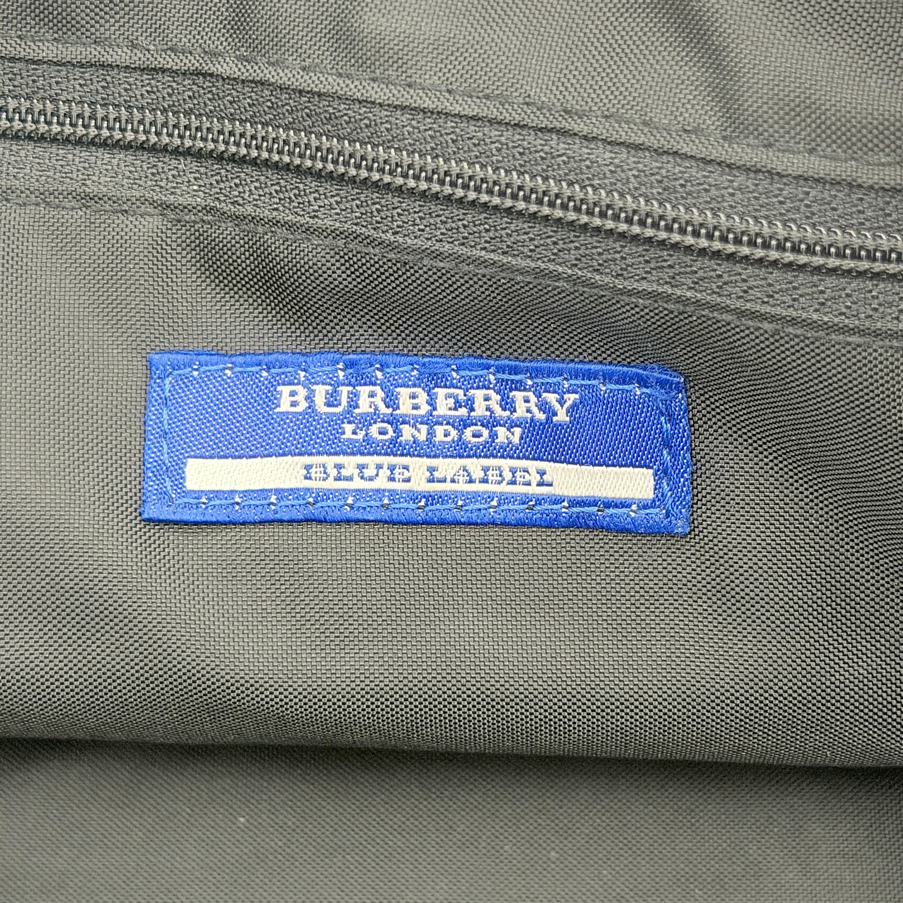 Burberry Blue Label Nova Check nylon shoulder bag in beige and black with leather handles, displayed against a white background.