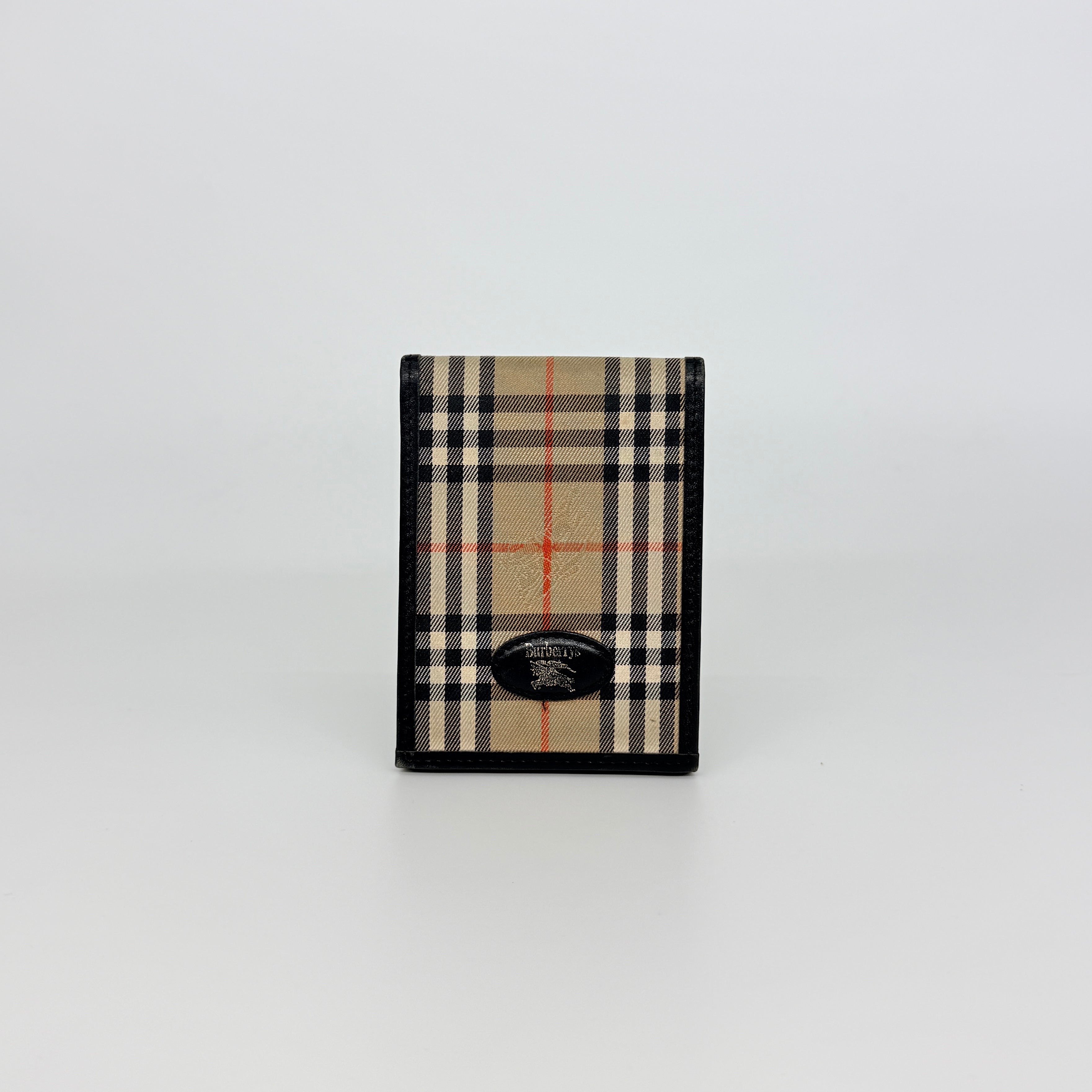 Front-facing view of a Burberry Nova Check cardholder in beige canvas with black leather trim and an oval Burberrys plaque.