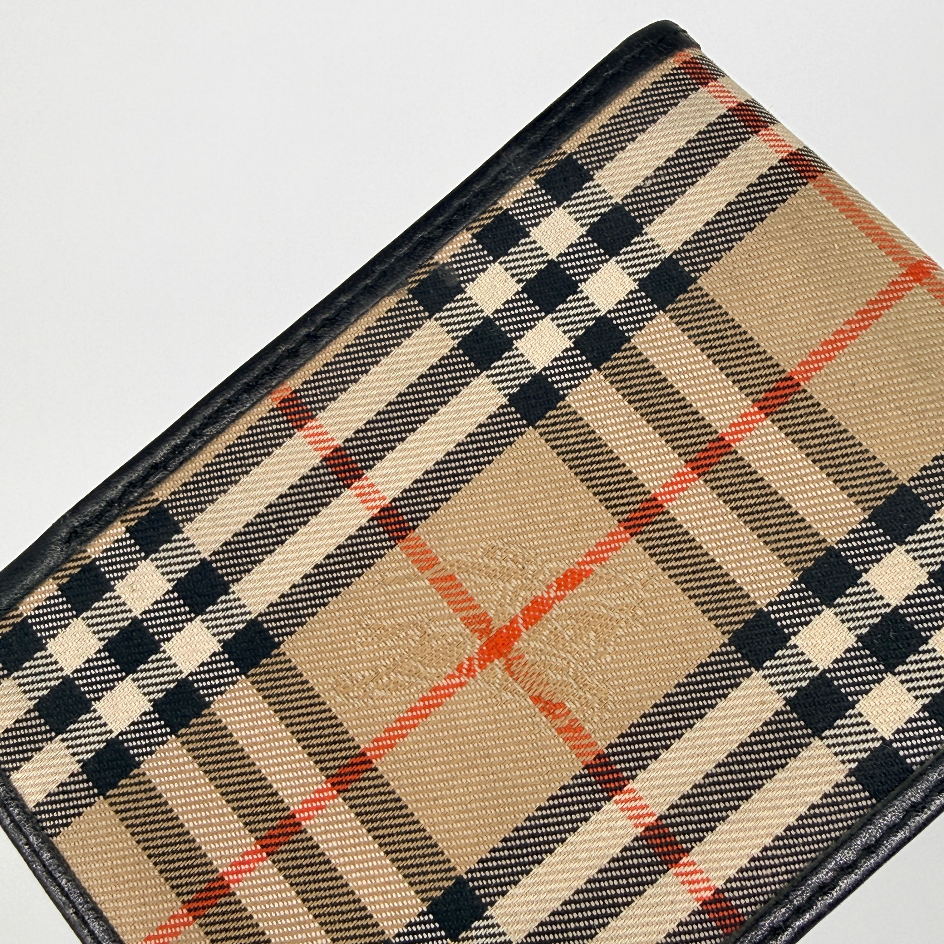 Front-facing view of a Burberry Nova Check cardholder in beige canvas with black leather trim and an oval Burberrys plaque.