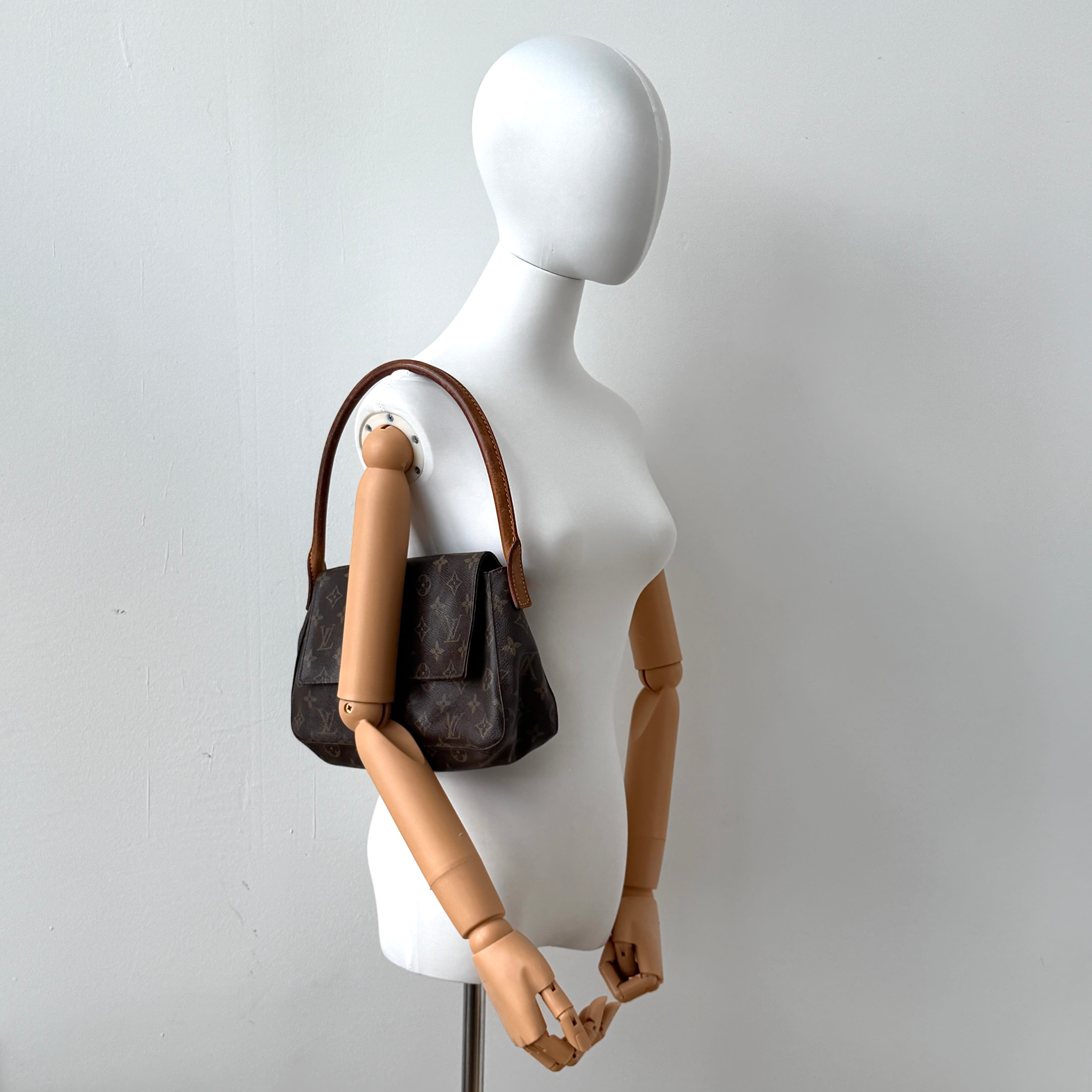 Louis Vuitton Monogram Mini Looping Shoulder Bag in brown monogram canvas with curved vachetta leather shoulder strap displayed upright.