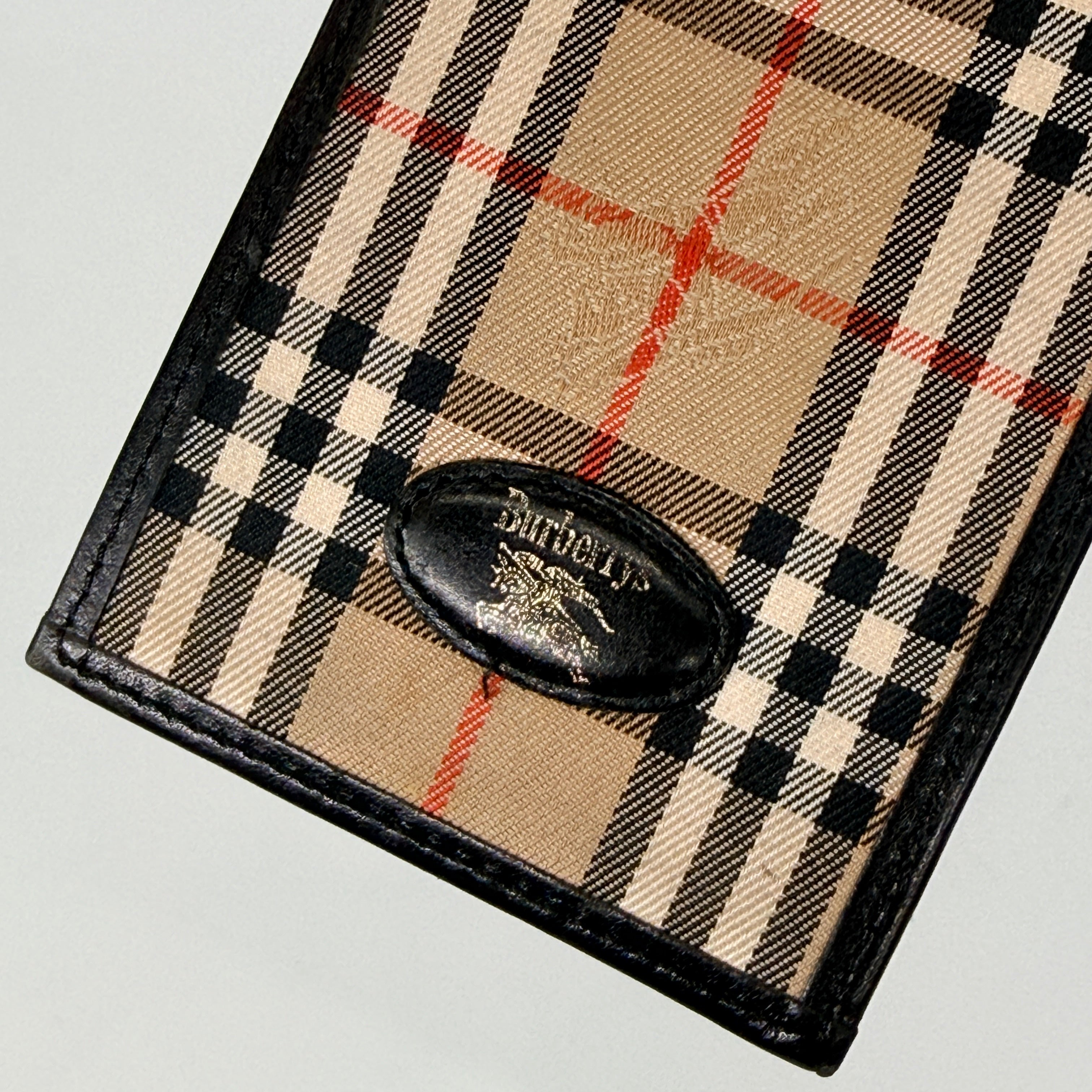 Front-facing view of a Burberry Nova Check cardholder in beige canvas with black leather trim and an oval Burberrys plaque.