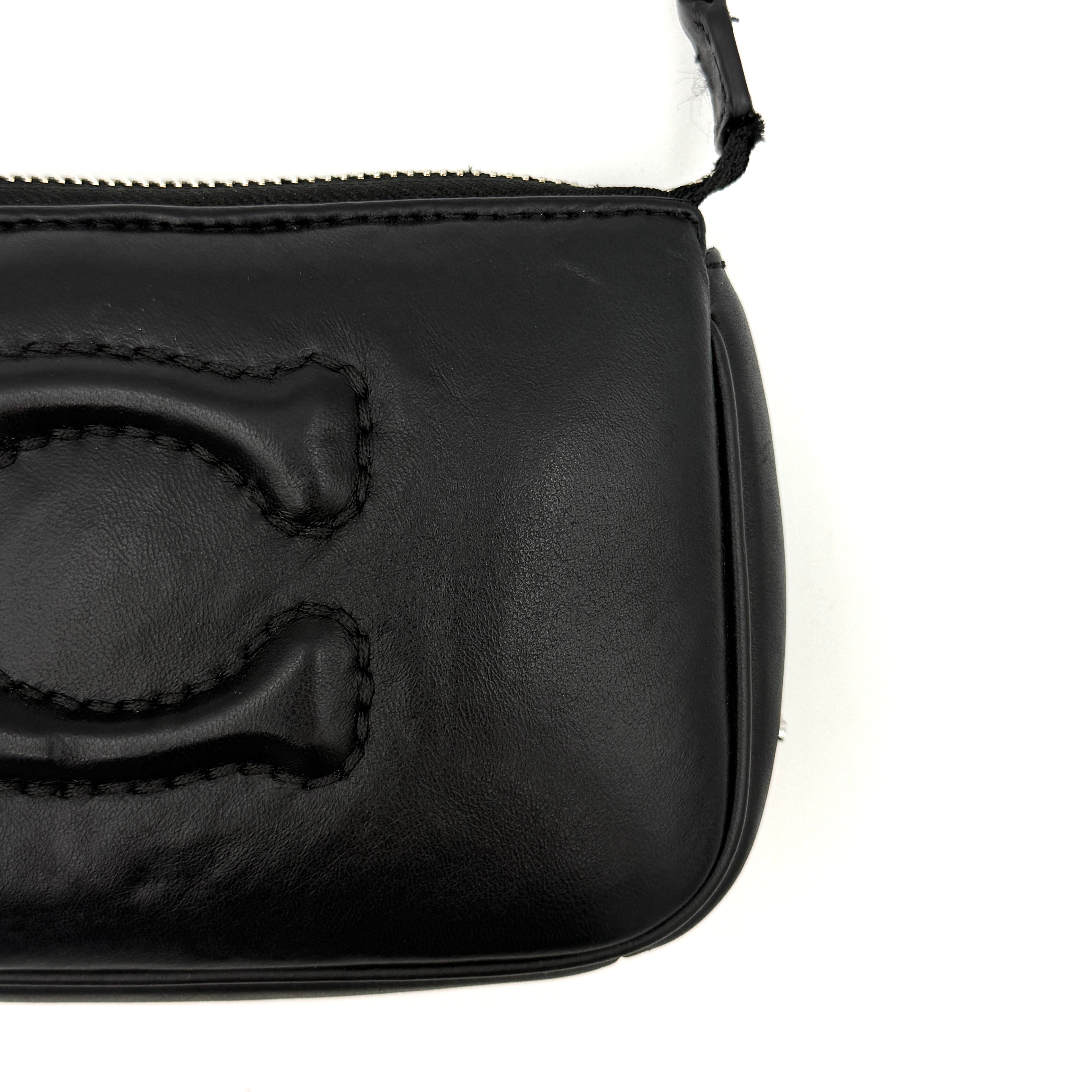 Coach Nolita 19 shoulder bag in quilted black leather with a bold stitched 'C' emblem and chunky silver chain strap.