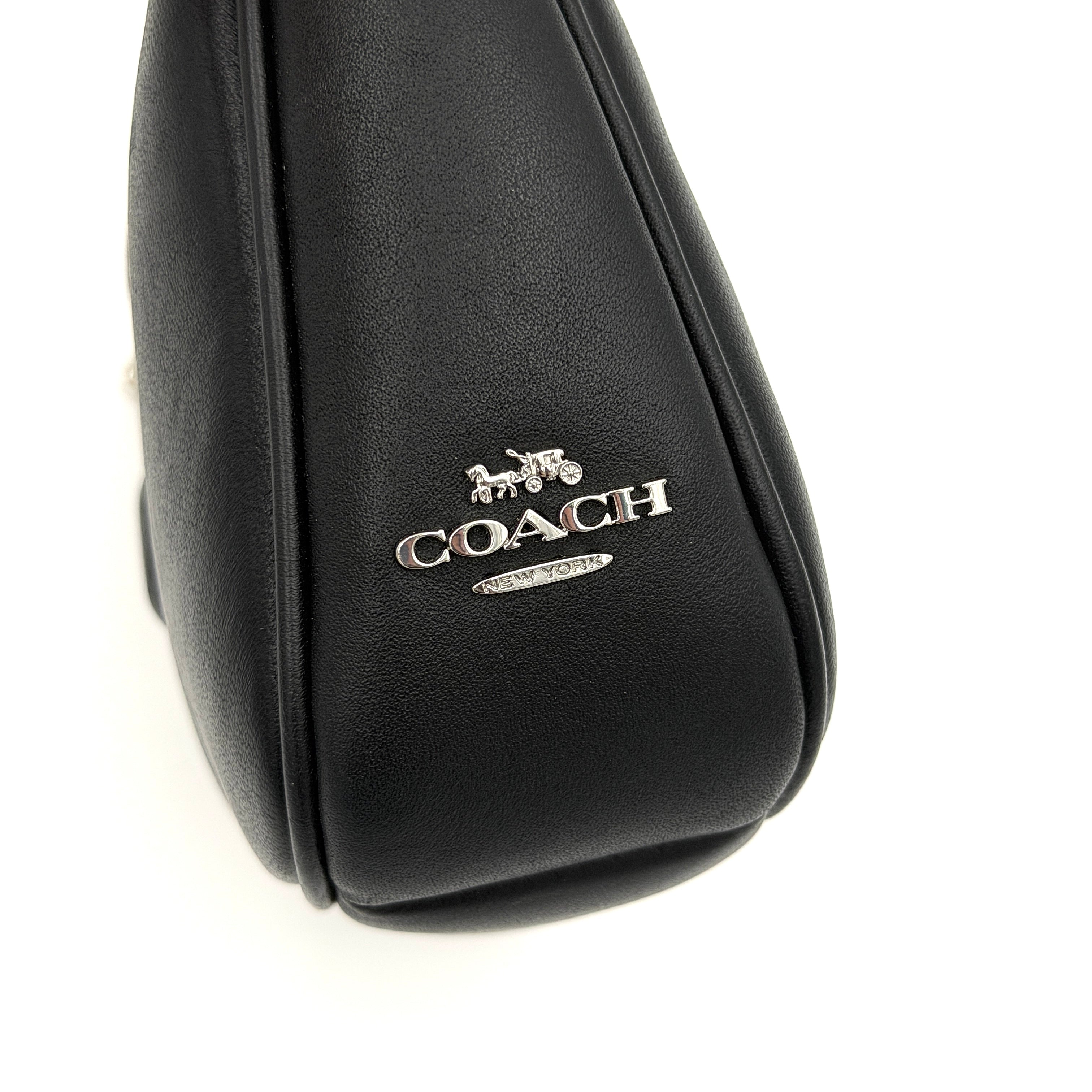 Coach Nolita 19 shoulder bag in quilted black leather with a bold stitched 'C' emblem and chunky silver chain strap.