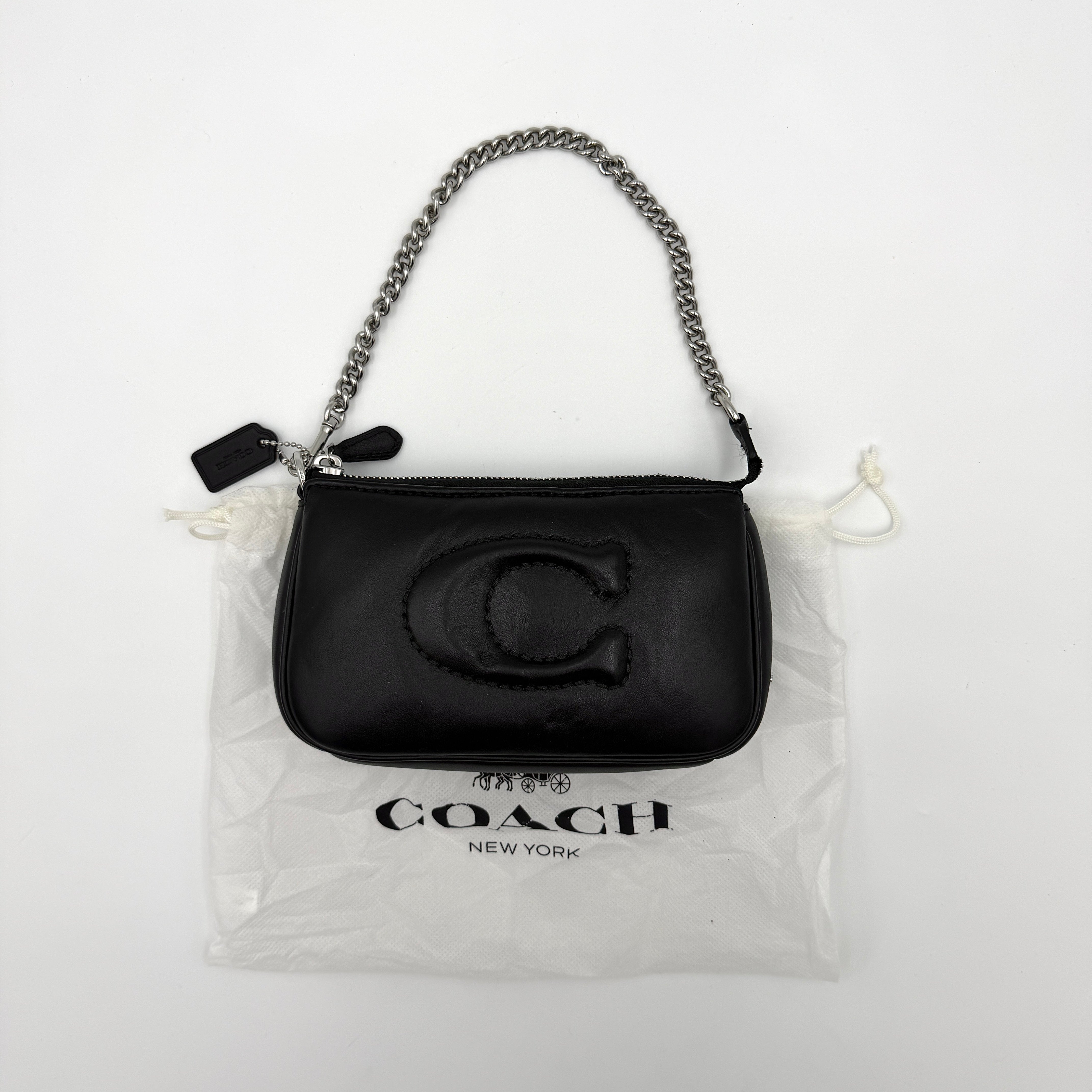 Coach Nolita 19 shoulder bag in quilted black leather with a bold stitched 'C' emblem and chunky silver chain strap.