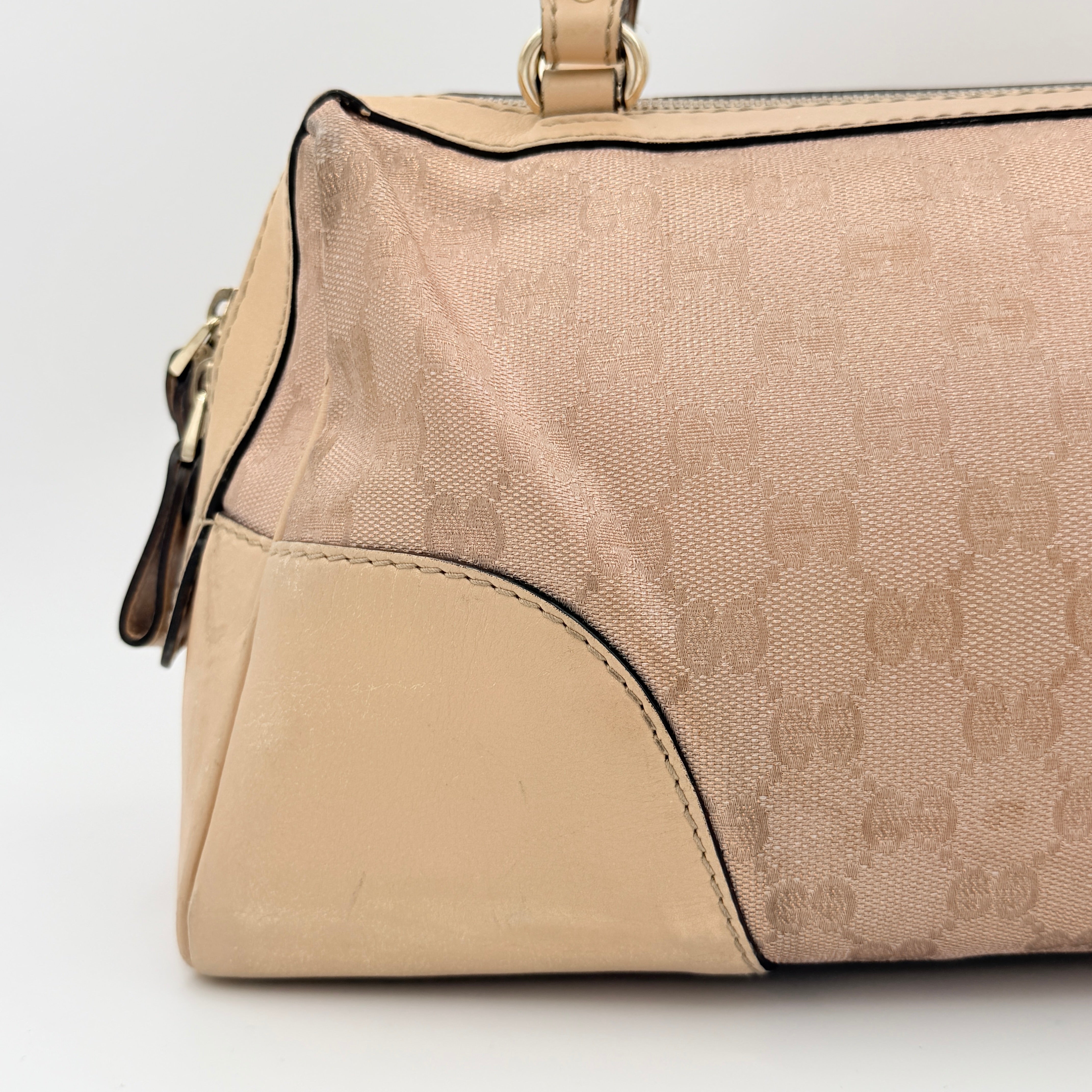 Gucci GG Monogram Heart Lovely Boston Bag in beige and pink with gold heart logo and double handles, displayed against a plain background.