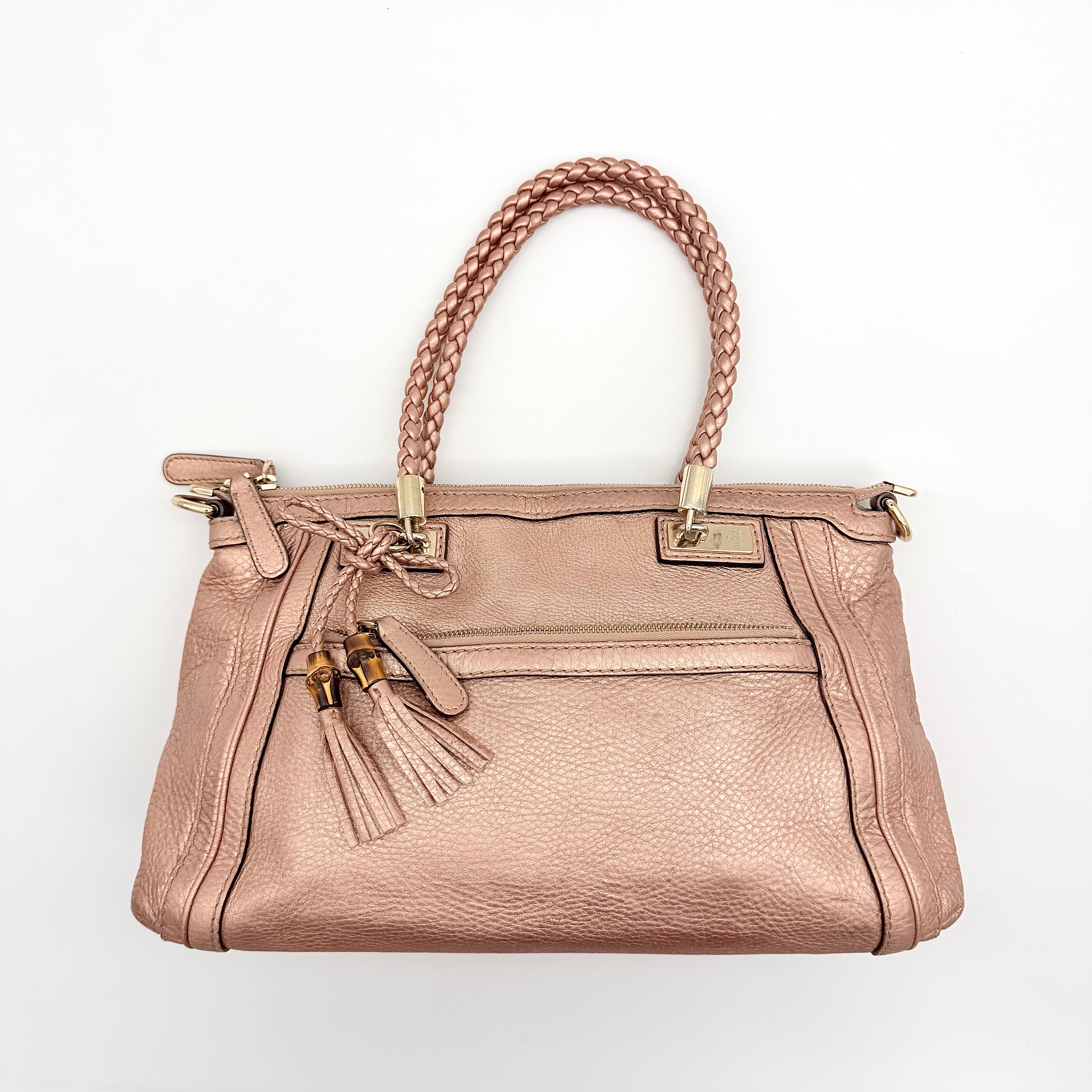 Gucci Bella Bamboo 2Way shoulder bag in metallic pink leather with braided handles and bamboo tassel accents, displayed with a detachable strap.
