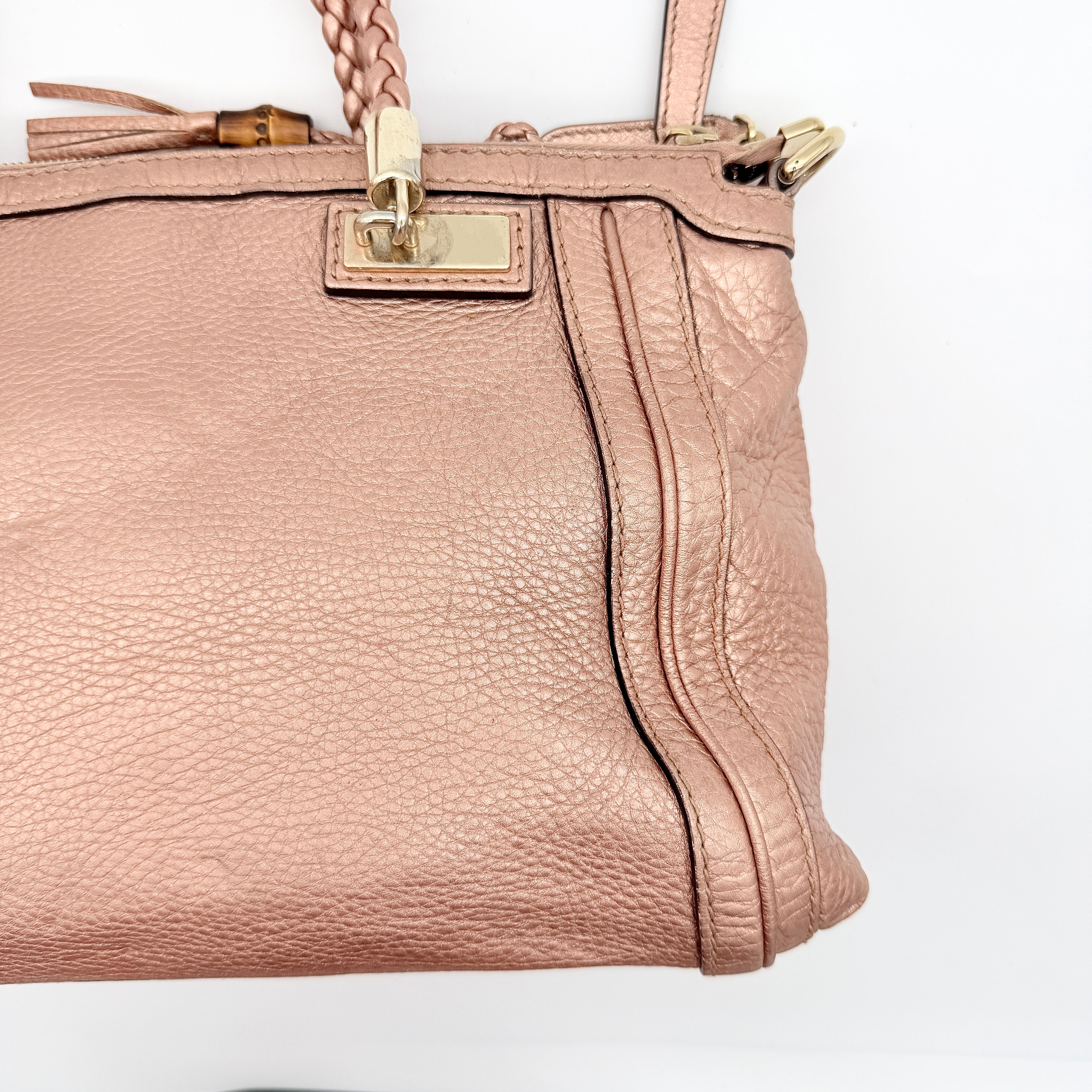 Gucci Bella Bamboo 2Way shoulder bag in metallic pink leather with braided handles and bamboo tassel accents, displayed with a detachable strap.