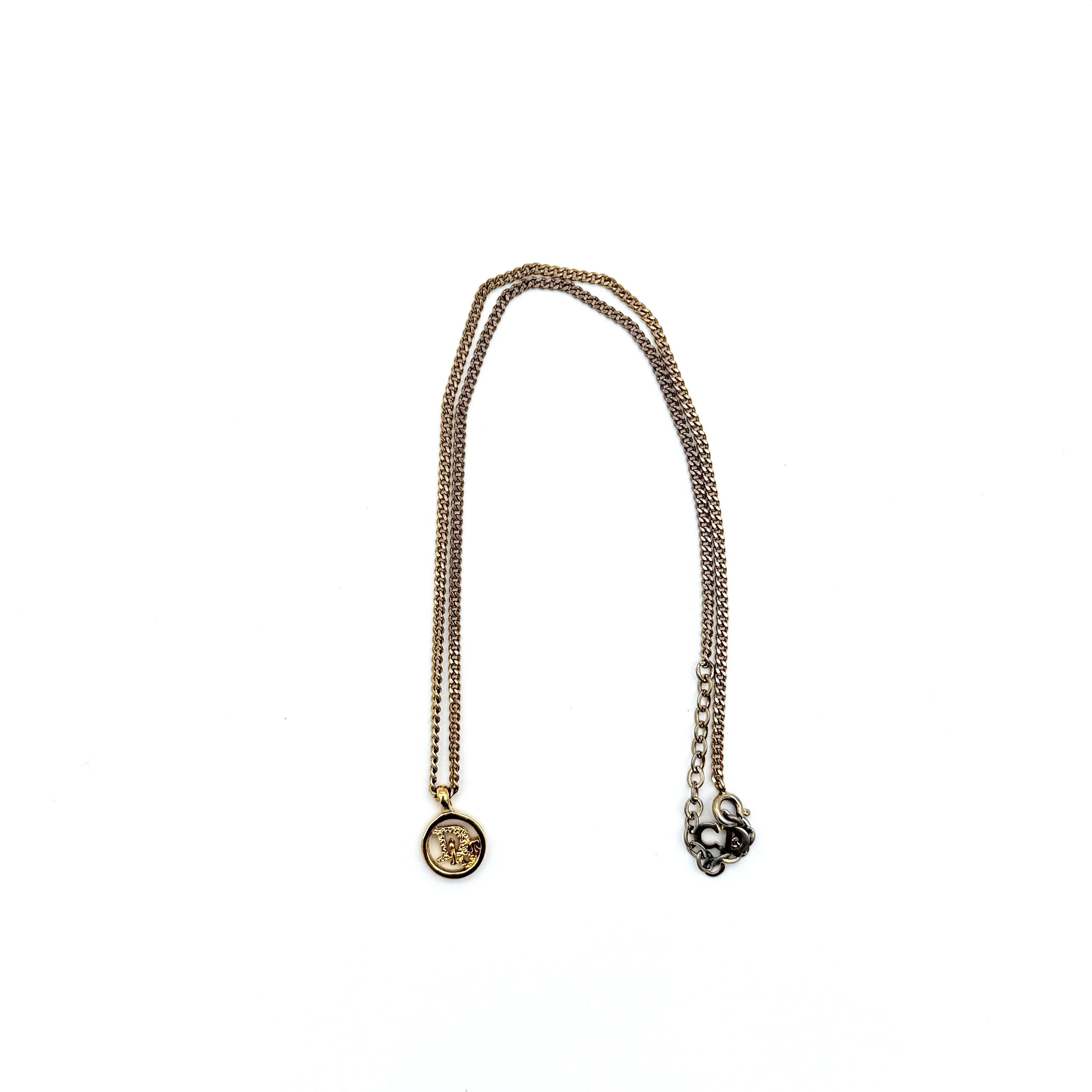 Dior gold-tone necklace featuring a circular logo pendant displayed on a necklace stand.