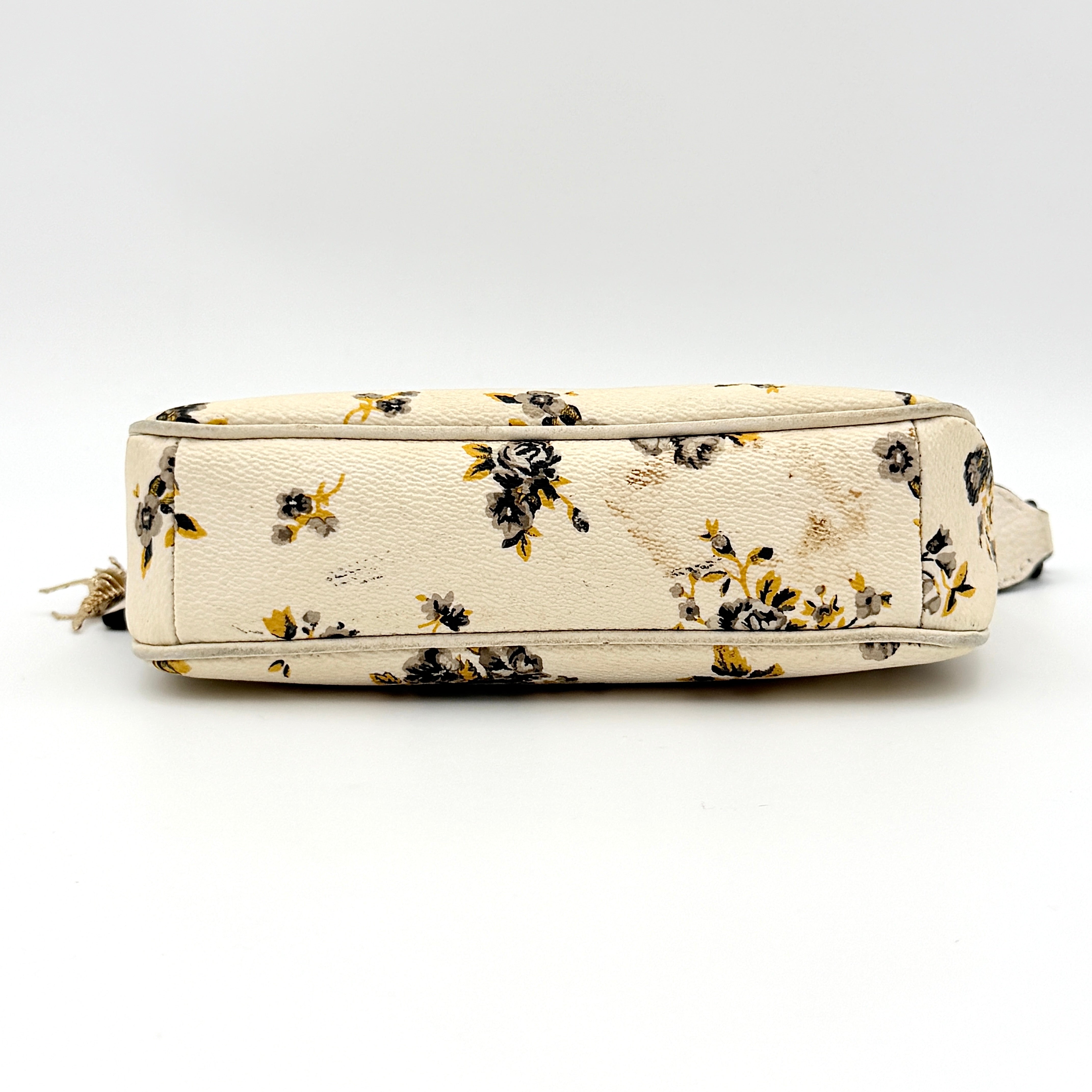 Coach Nolita 19 shoulder bag in white pebbled leather with yellow and grey floral print, chunky gunmetal chain strap, and decorative charms.