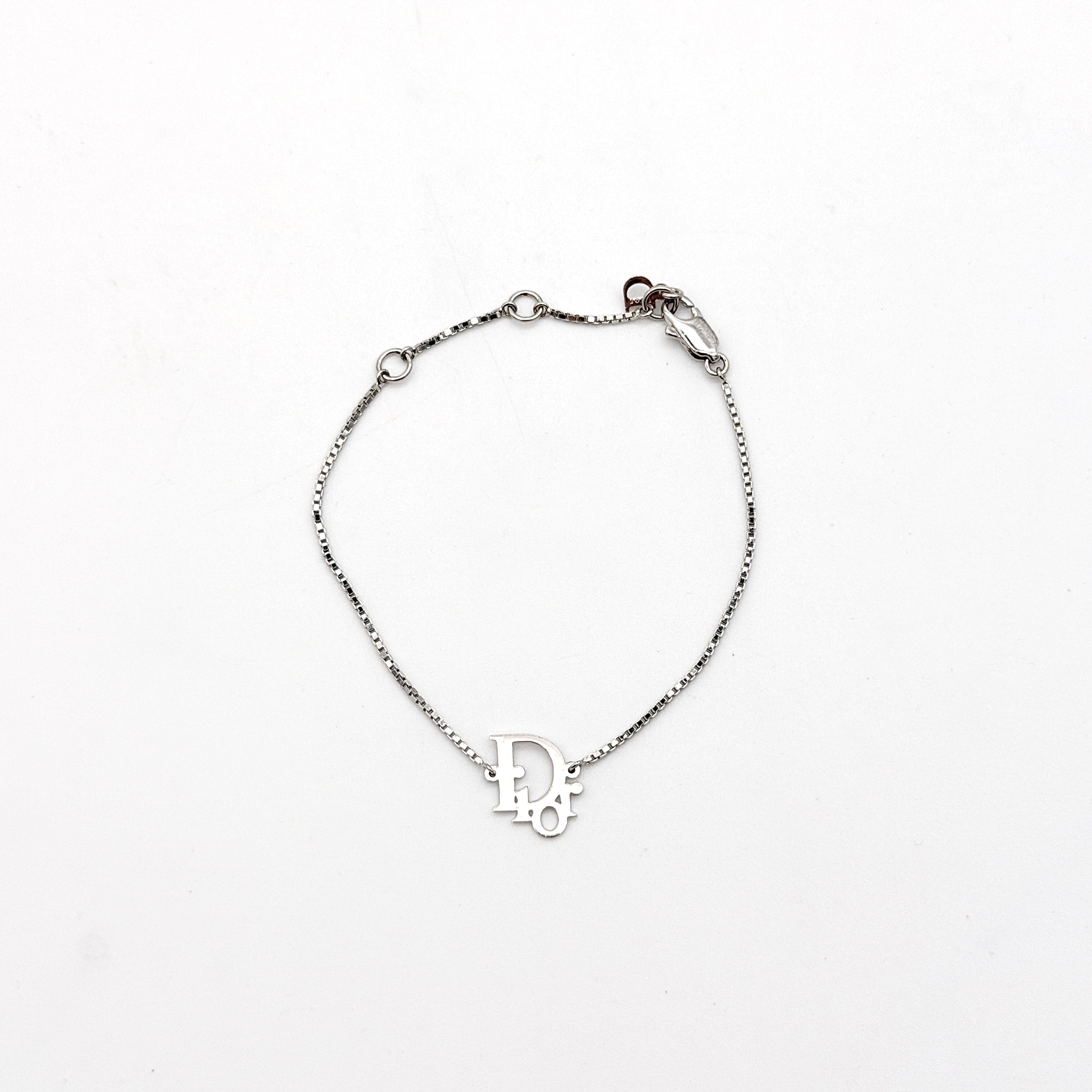 Dior silver logo bracelet with fine box chain and central branded charm photographed on a white background.
