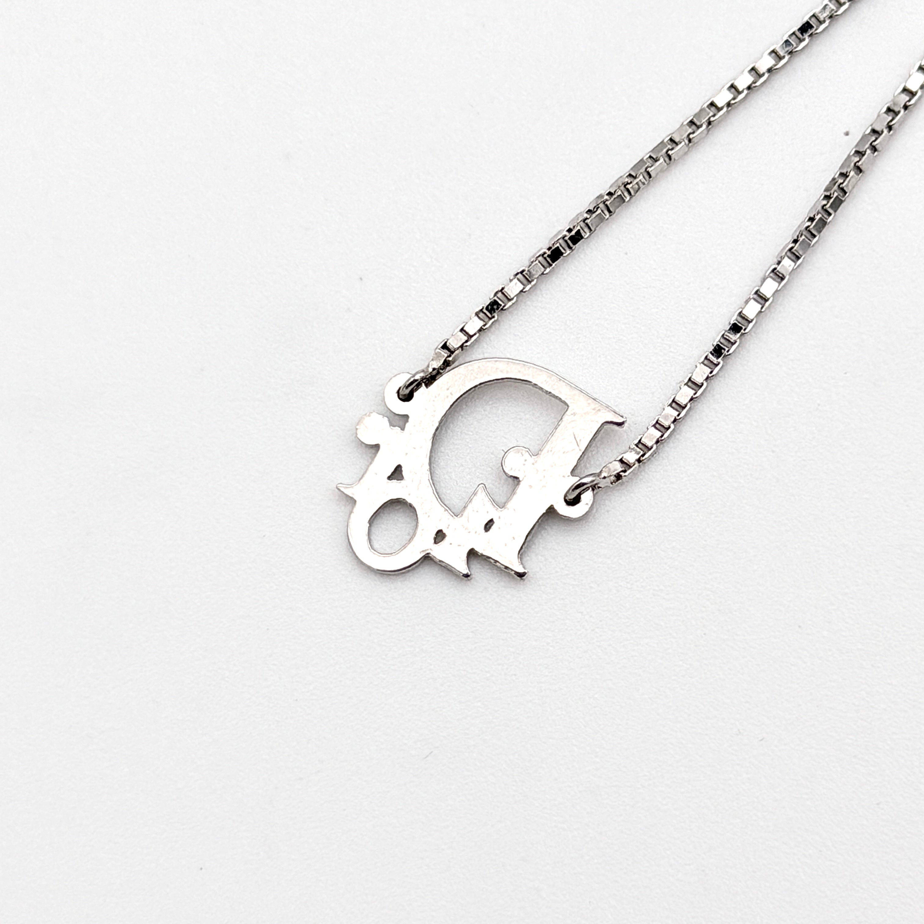 Dior silver logo bracelet with fine box chain and central branded charm photographed on a white background.