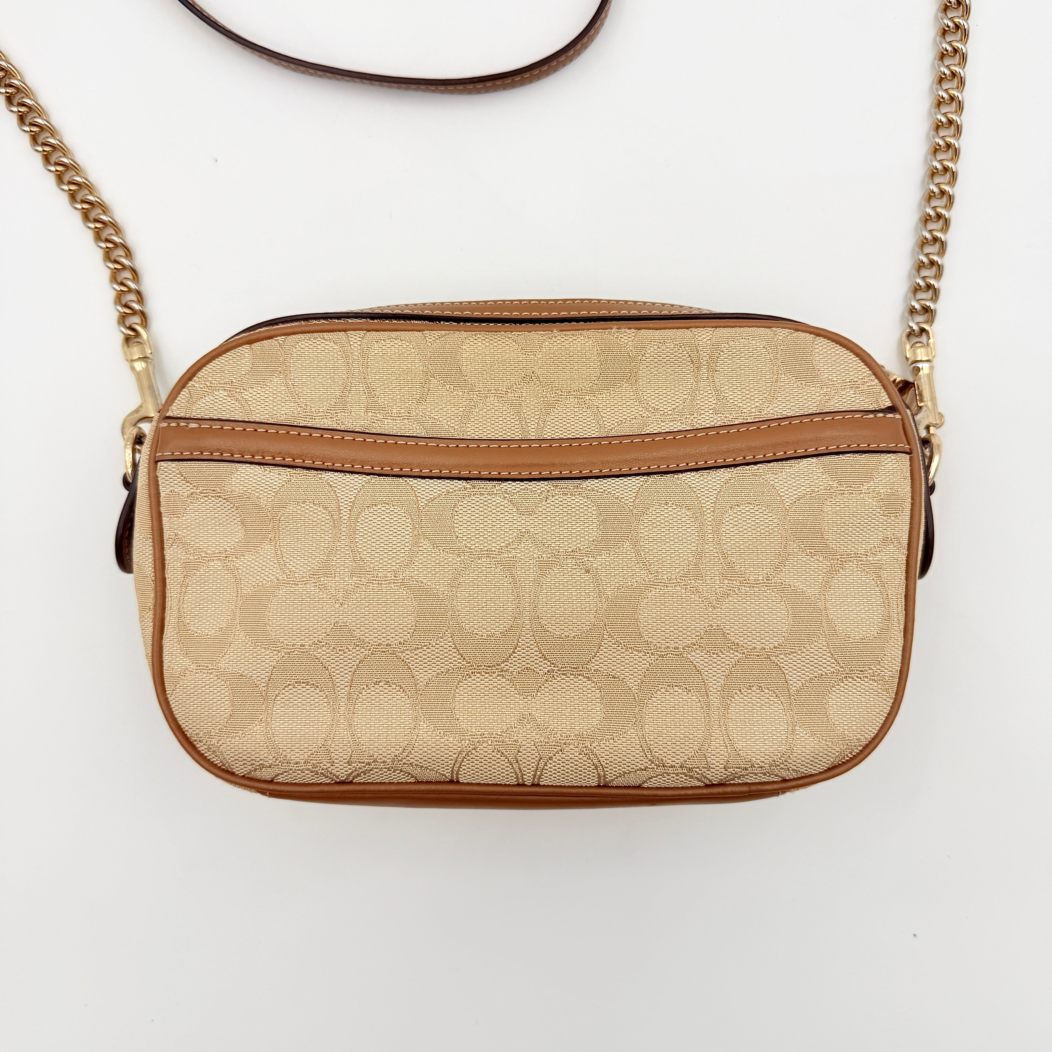 Coach Signature Isla Chain Crossbody Bag in beige and brown jacquard with caramel leather trim and gold-tone chain strap.