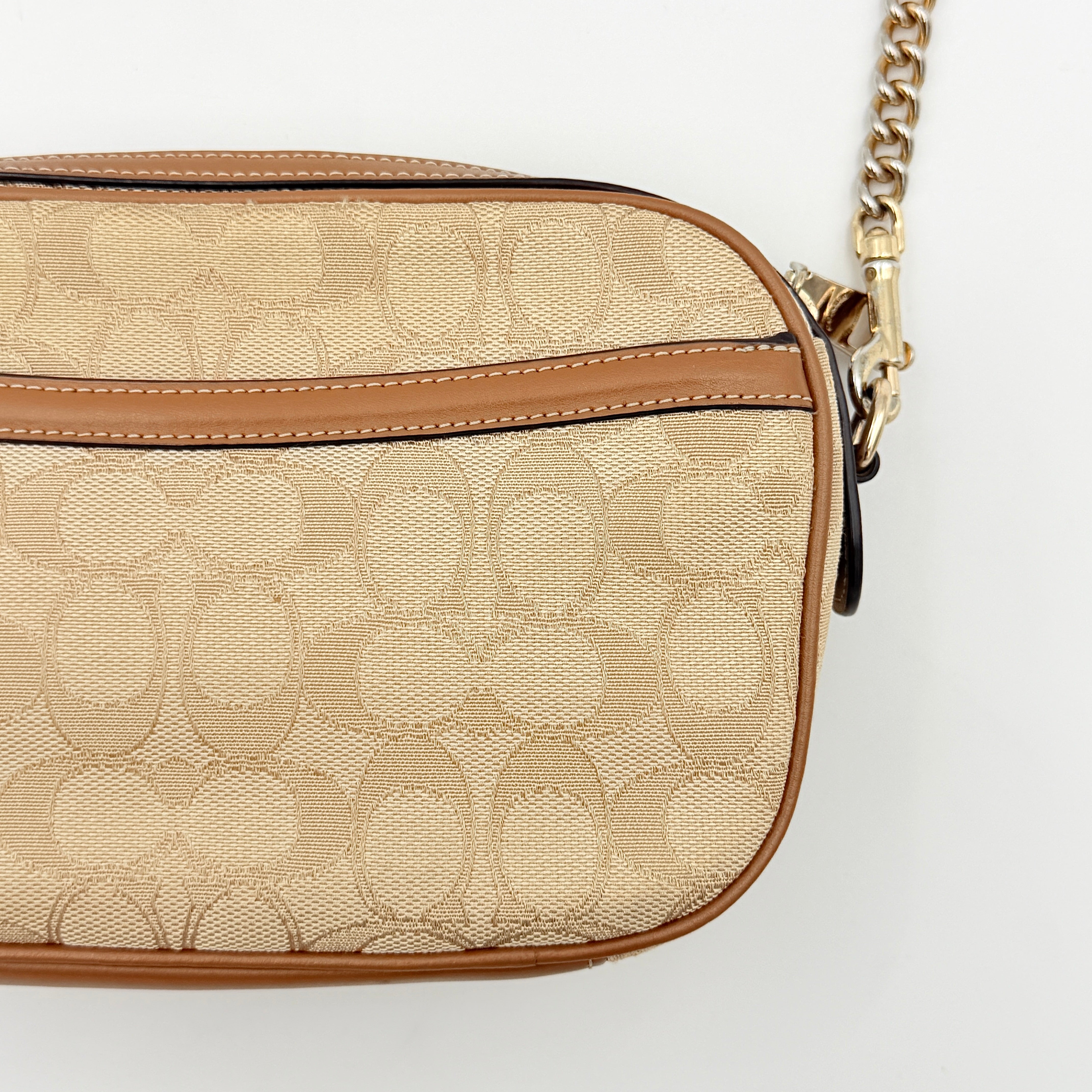 Coach Signature Isla Chain Crossbody Bag in beige and brown jacquard with caramel leather trim and gold-tone chain strap.