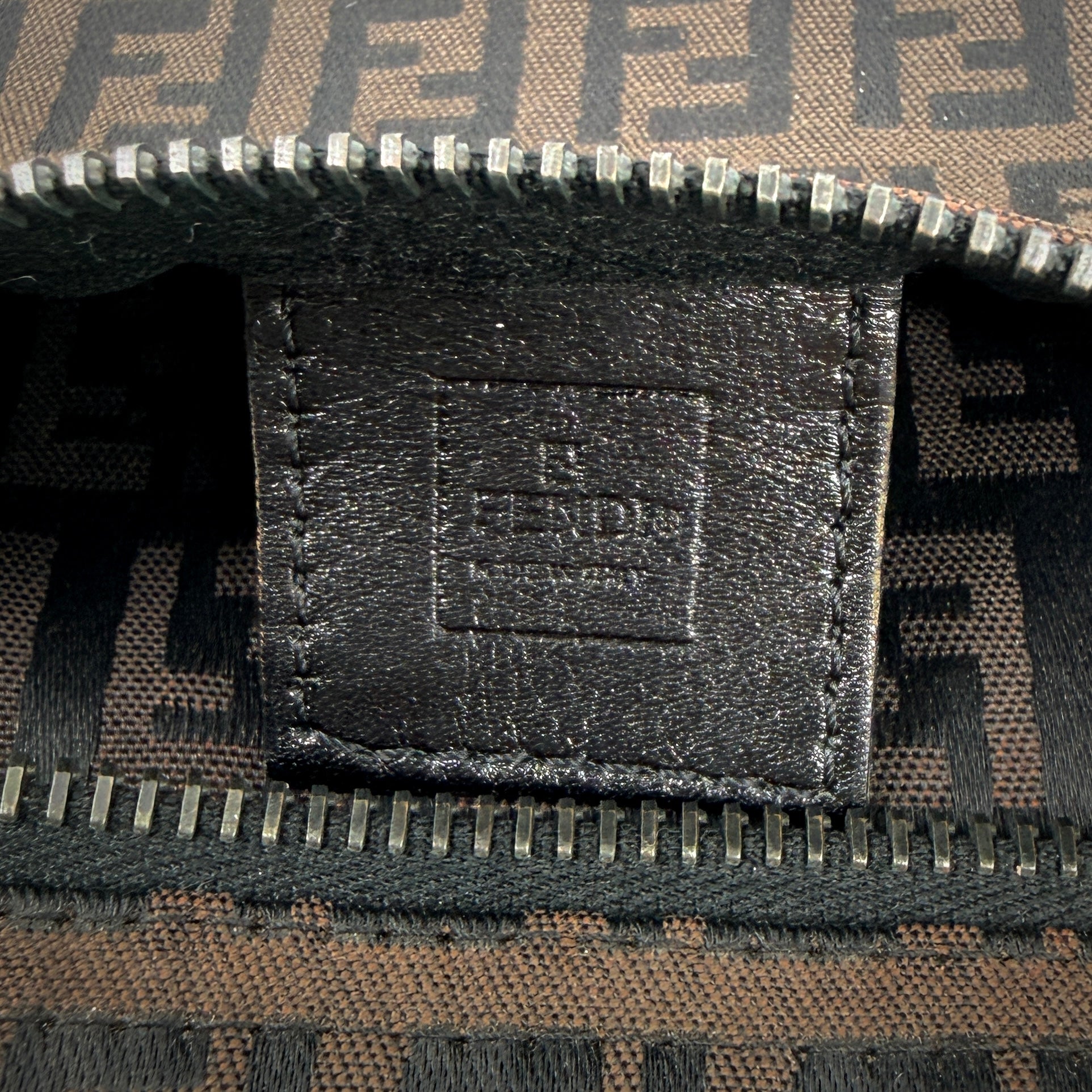 The Fendi FF Zucca Pouch in brown canvas, featuring an all-over FF logo pattern and silver-tone zip closure.