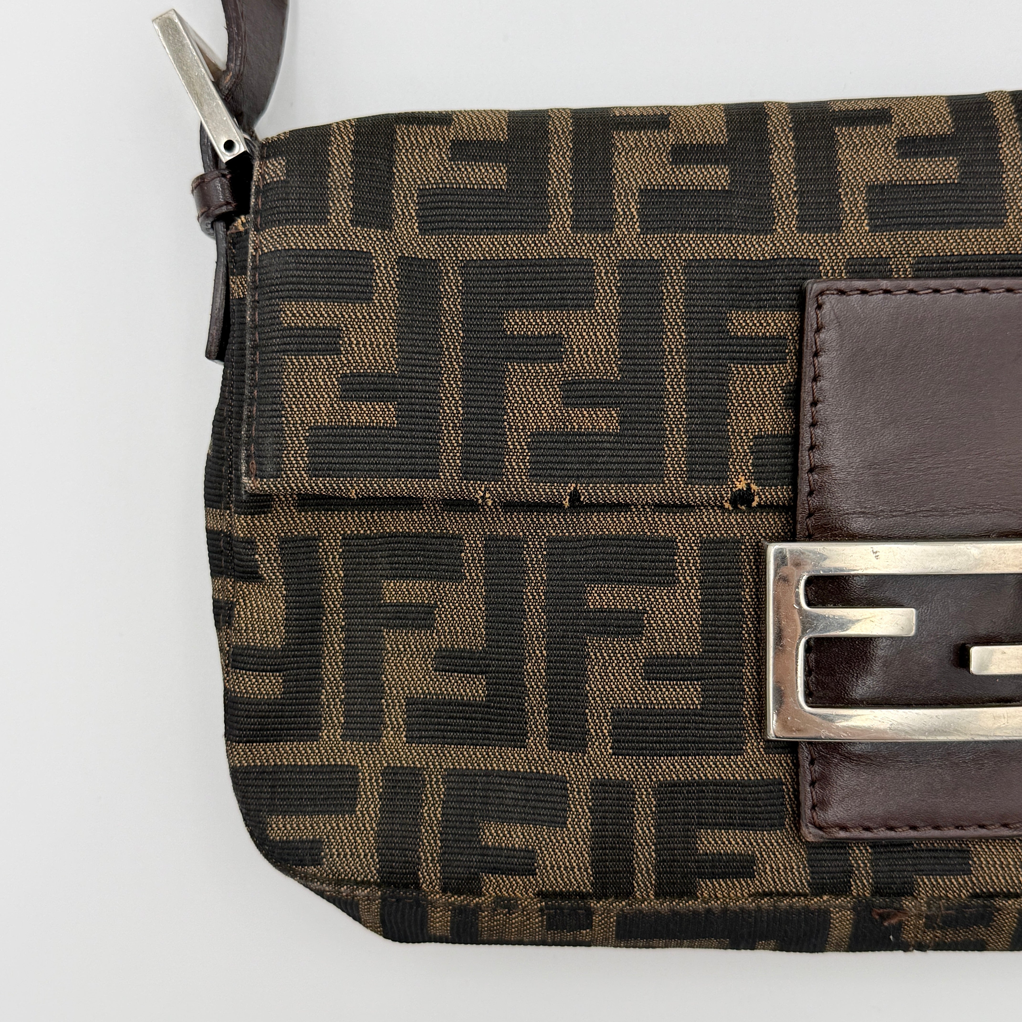 Fendi Zucca Print Baguette Bag in brown monogram canvas with silver-tone FF clasp and leather trim shown against a white background.