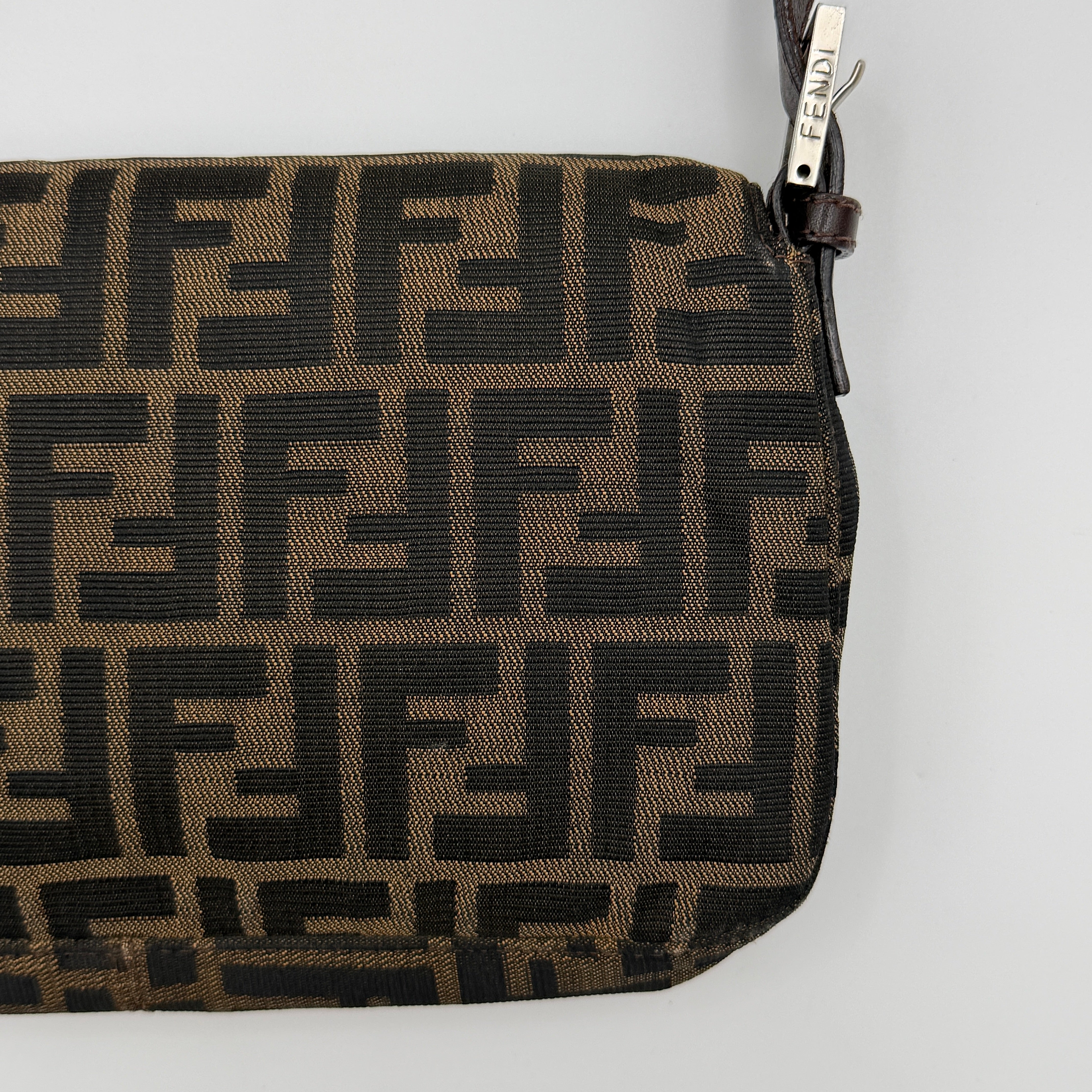 Fendi Zucca Print Baguette Bag in brown monogram canvas with silver-tone FF clasp and leather trim shown against a white background.