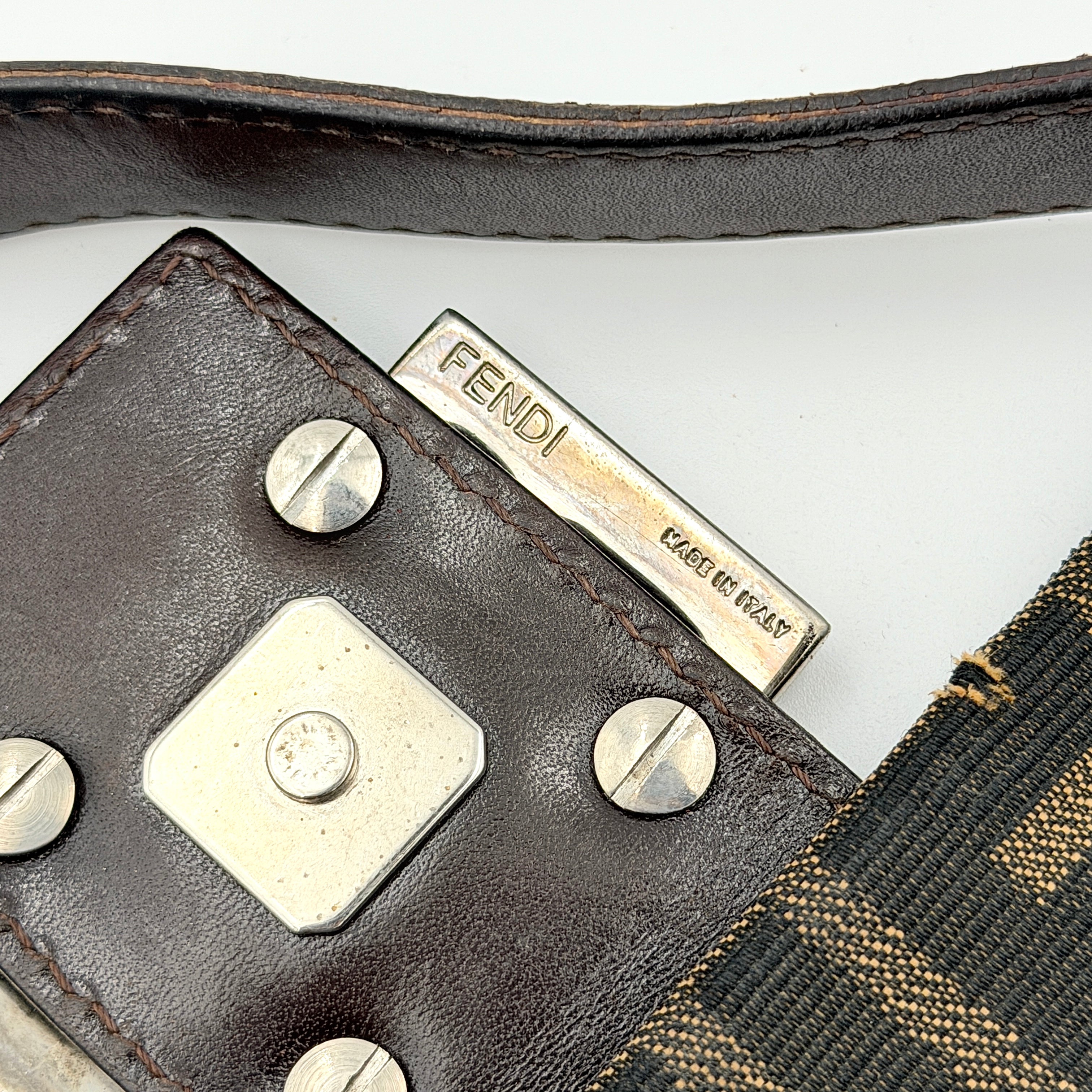 Fendi Zucca Print Baguette Bag in brown monogram canvas with silver-tone FF clasp and leather trim shown against a white background.