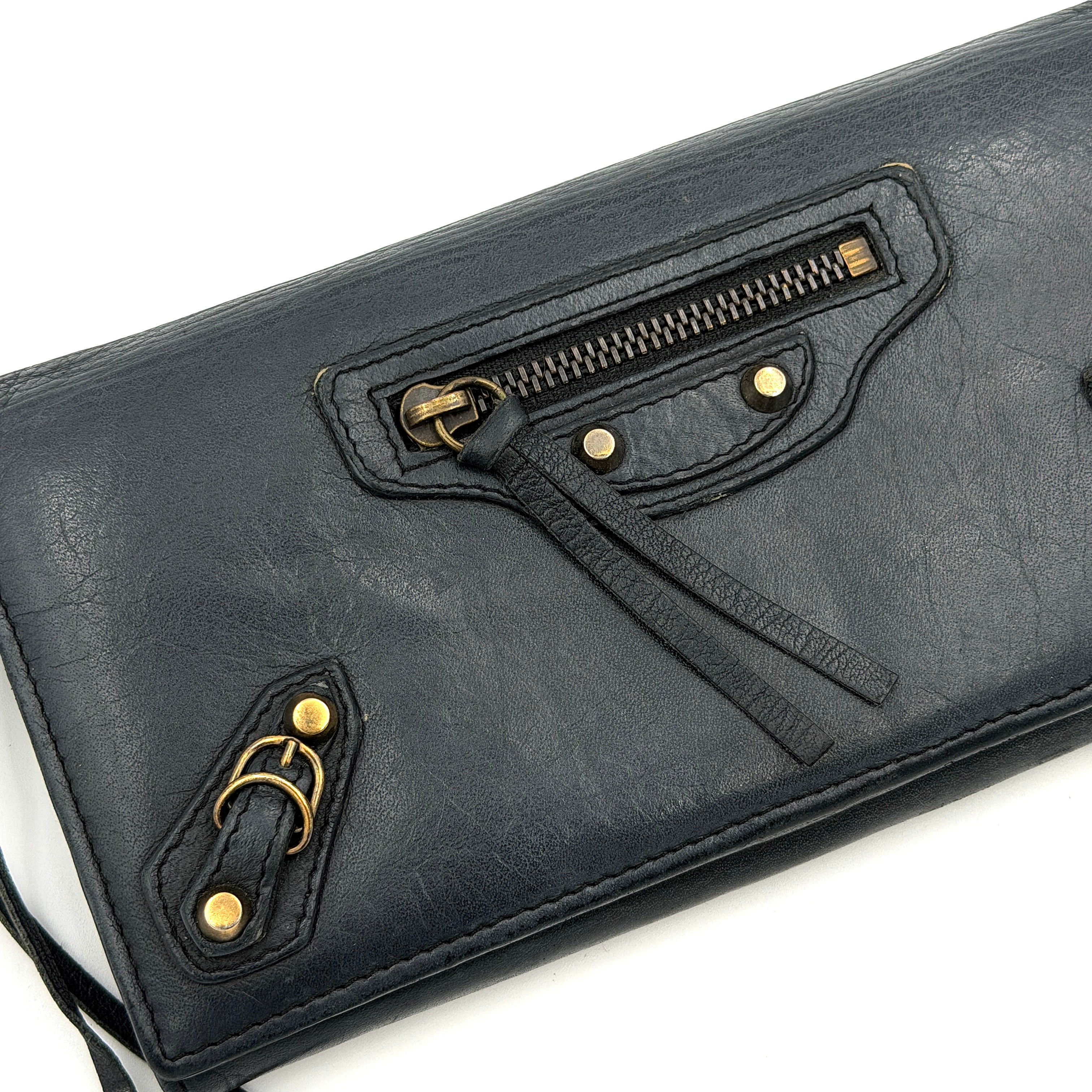 Balenciaga Agneau Leather Wallet in black with signature brass hardware and front zip detail, presented against a white background.