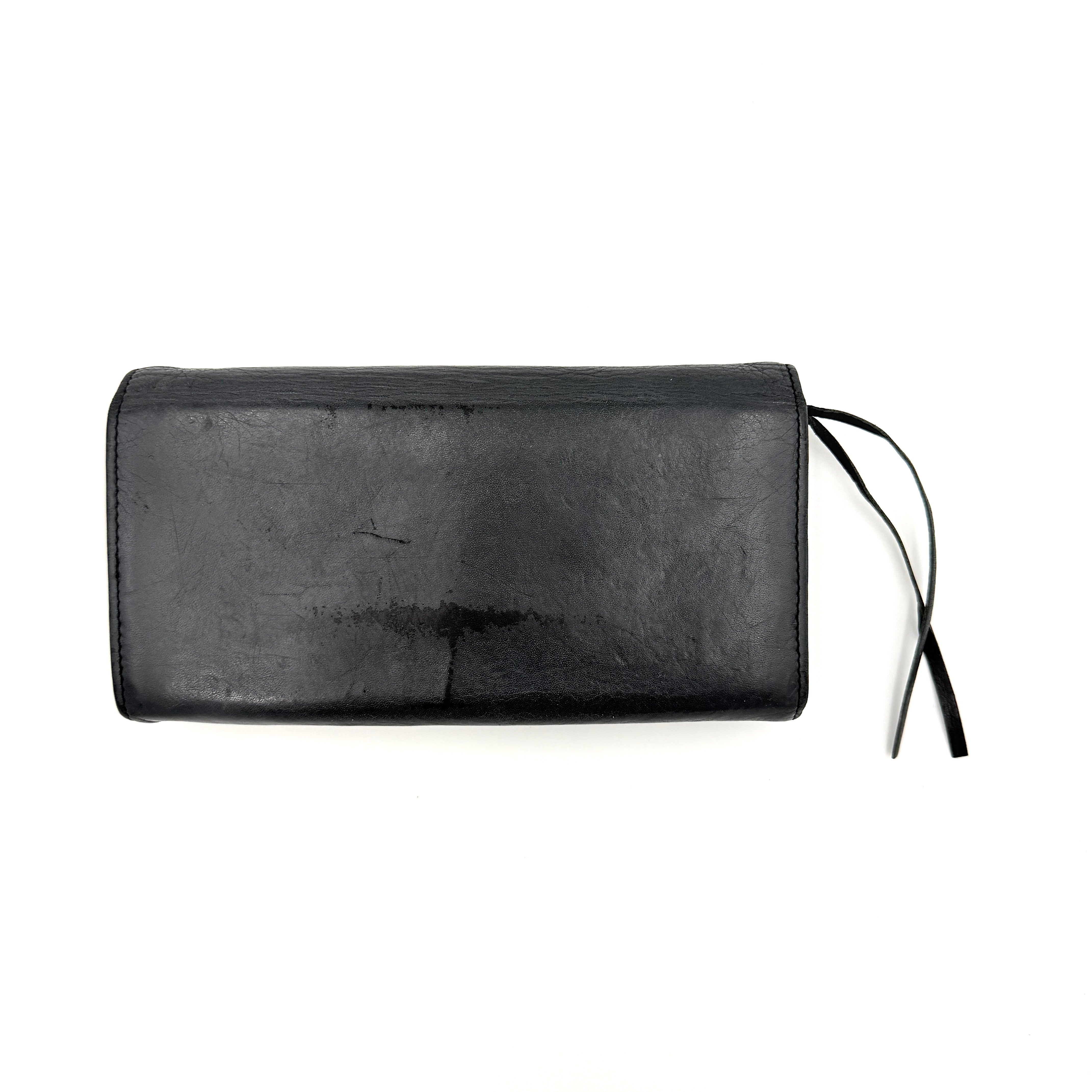 Balenciaga Agneau Leather Wallet in black with signature brass hardware and front zip detail, presented against a white background.