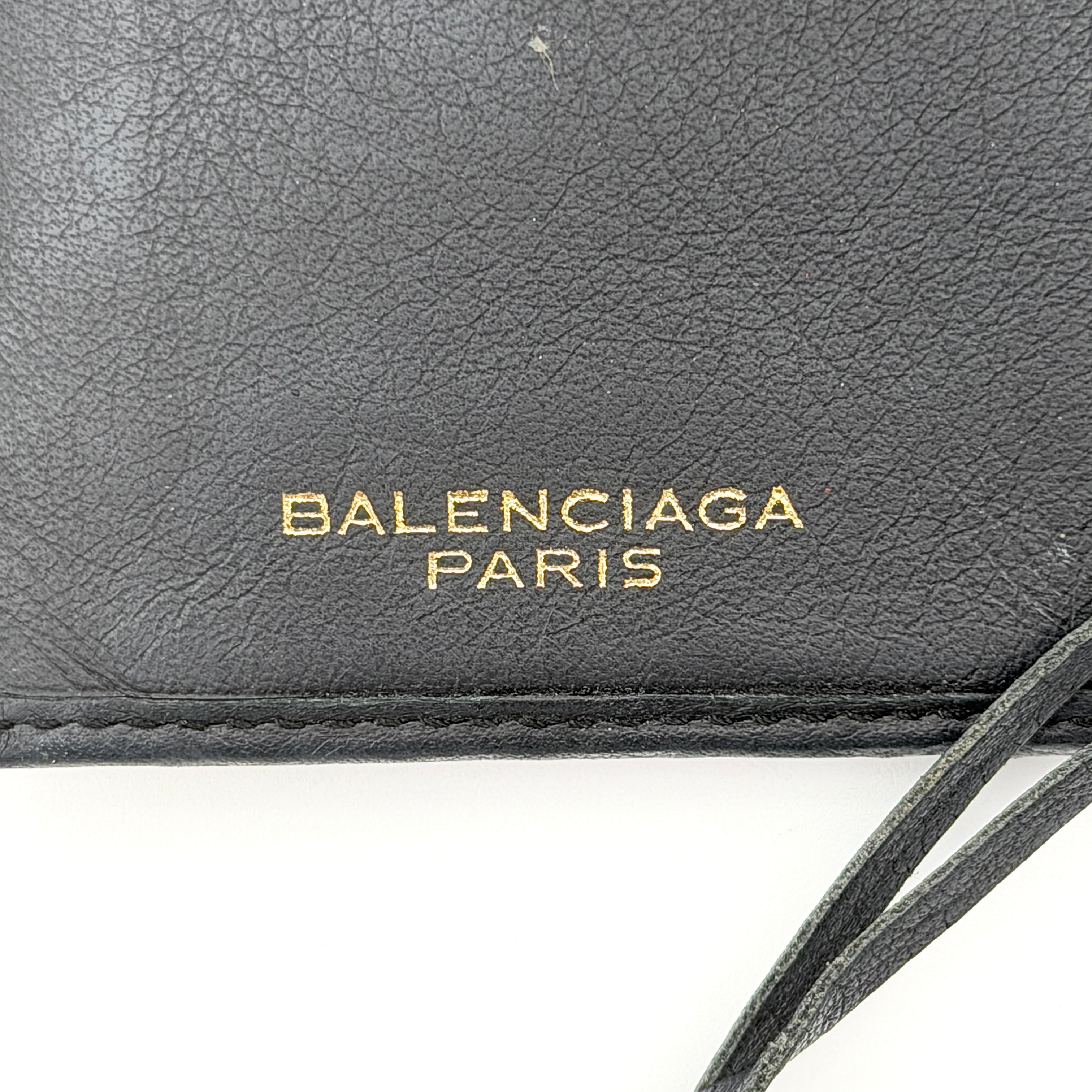 Balenciaga Agneau Leather Wallet in black with signature brass hardware and front zip detail, presented against a white background.