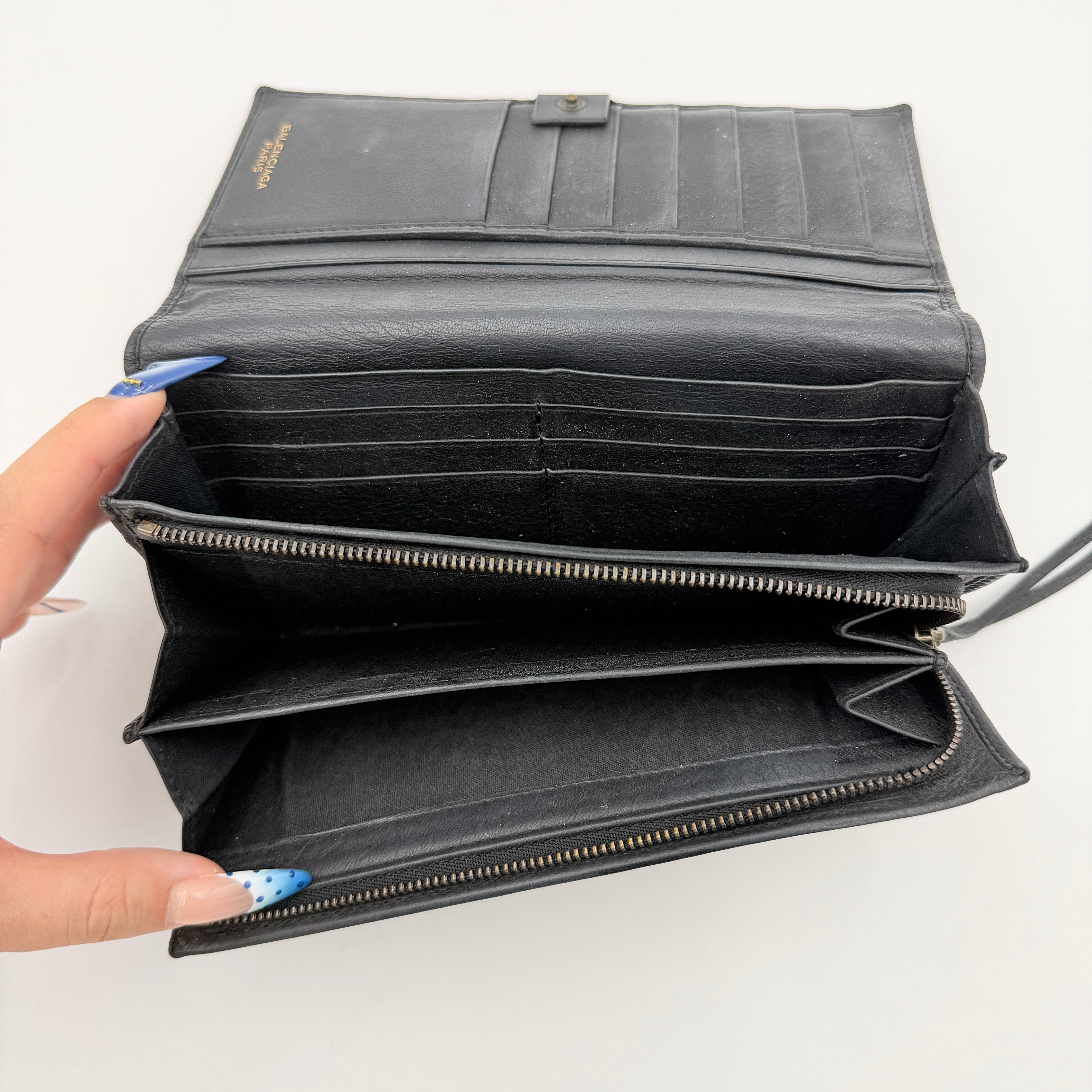 Balenciaga Agneau Leather Wallet in black with signature brass hardware and front zip detail, presented against a white background.