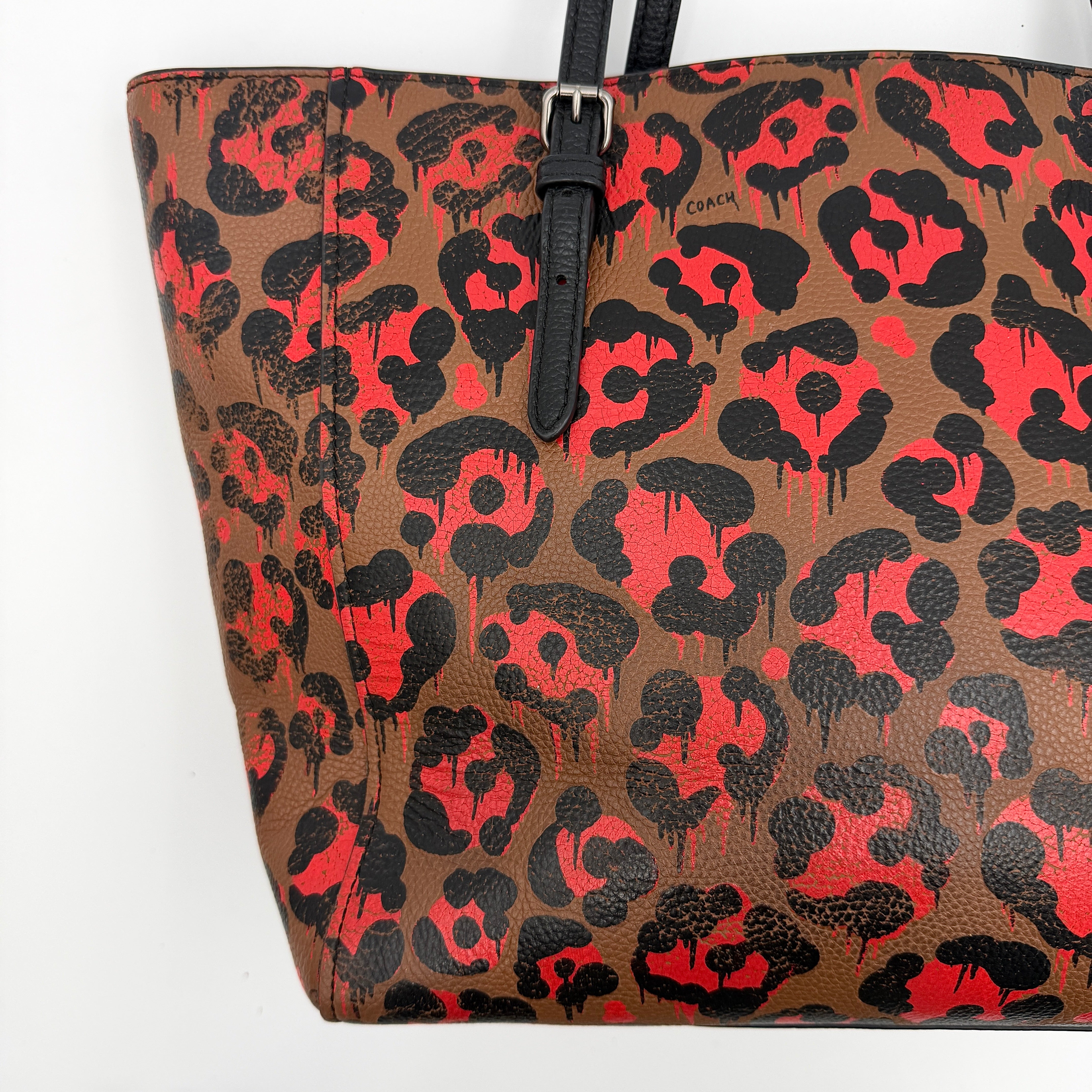Coach City Tote in brown coated canvas, drenched in a vivid red and black leopard print, with black leather handles and silver hardware details.
